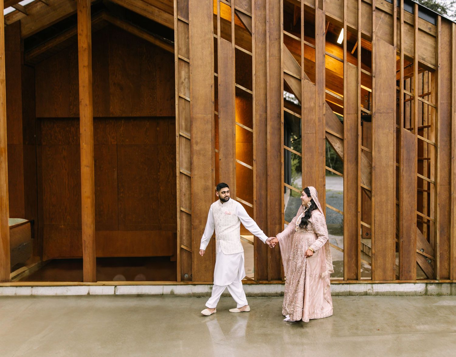 Bride and groom walking hand in hand at modern wedding venue White rock farm house.