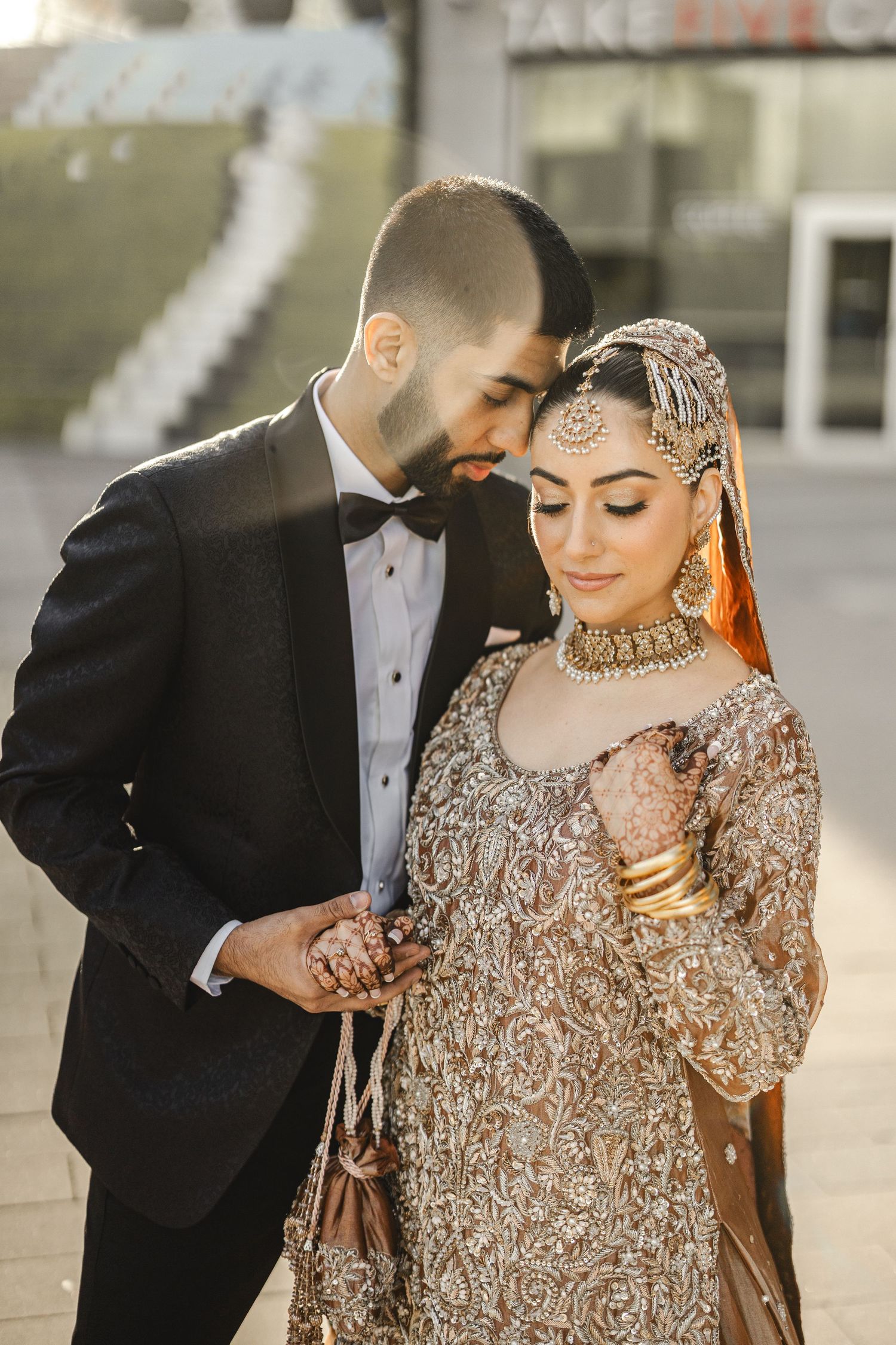 Bride in beaded gold gown with groom in black tuxedo, pre reception close portrait