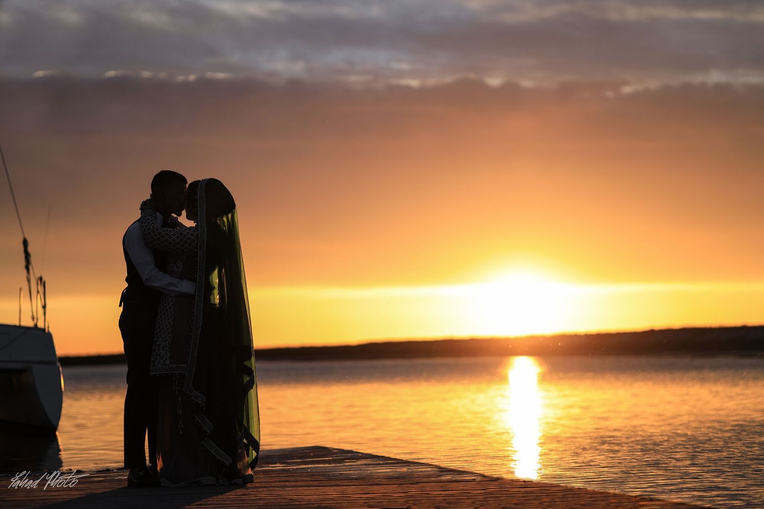 Silhouette of couple embracing at sunset over lake, golden hour engagement photos