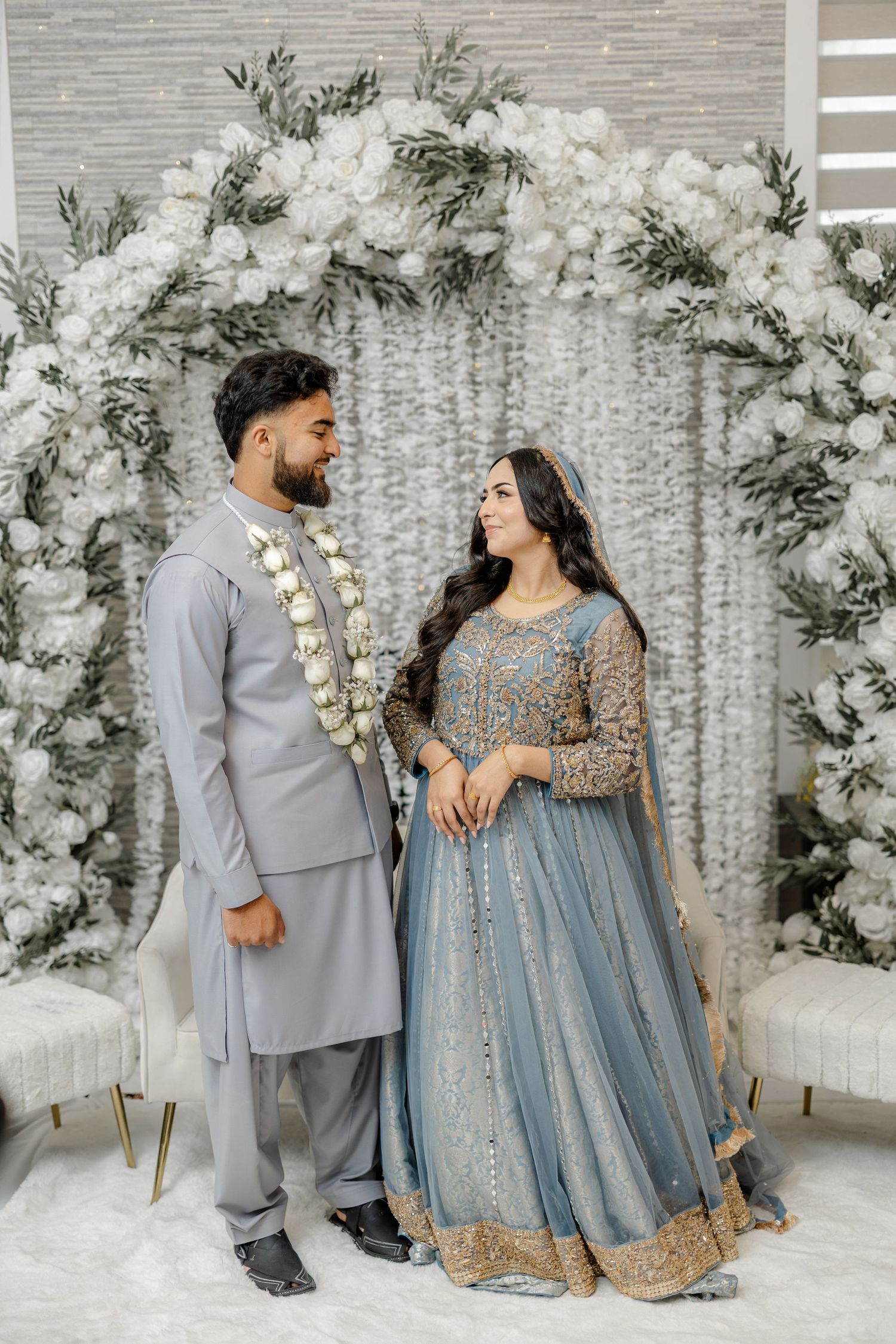 Bride and groom under floral arch, blue bridal lehenga, Nikah ceremony