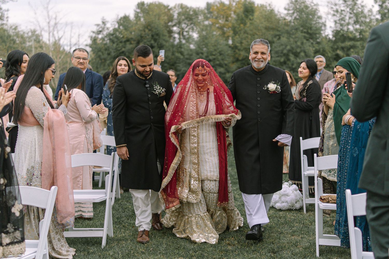 Bride walking down outdoor aisle with family, Nikah ceremony procession