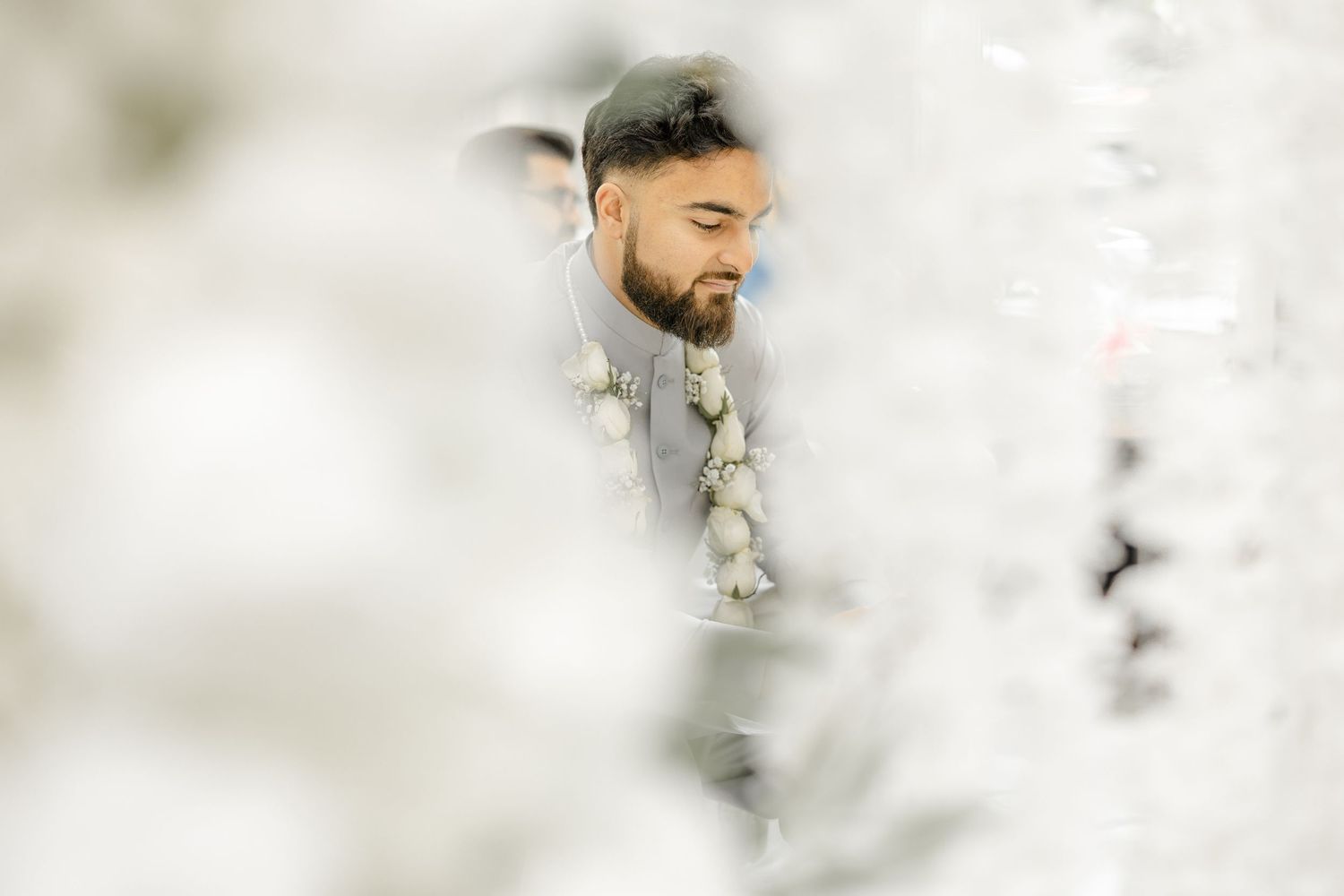 Groom in soft-focus portrait framed by foreground florals