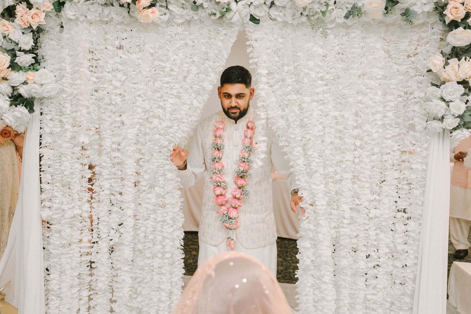 Groom standing under floral door going to meet the bride after Nikah