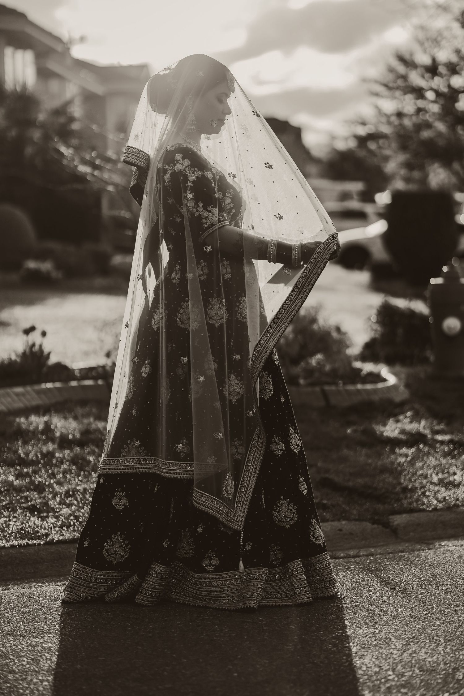 Bride in traditional outfit backlit against outdoor scenery