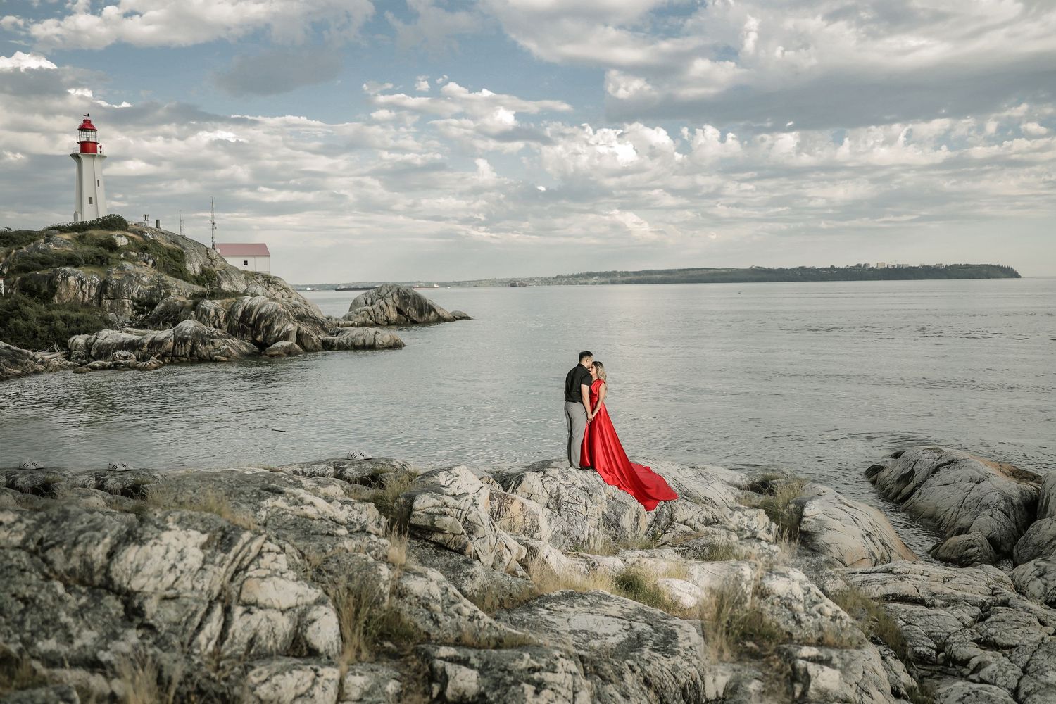 Bride in red gown by lighthouse on rocky BC coastline, engagement photoshoot