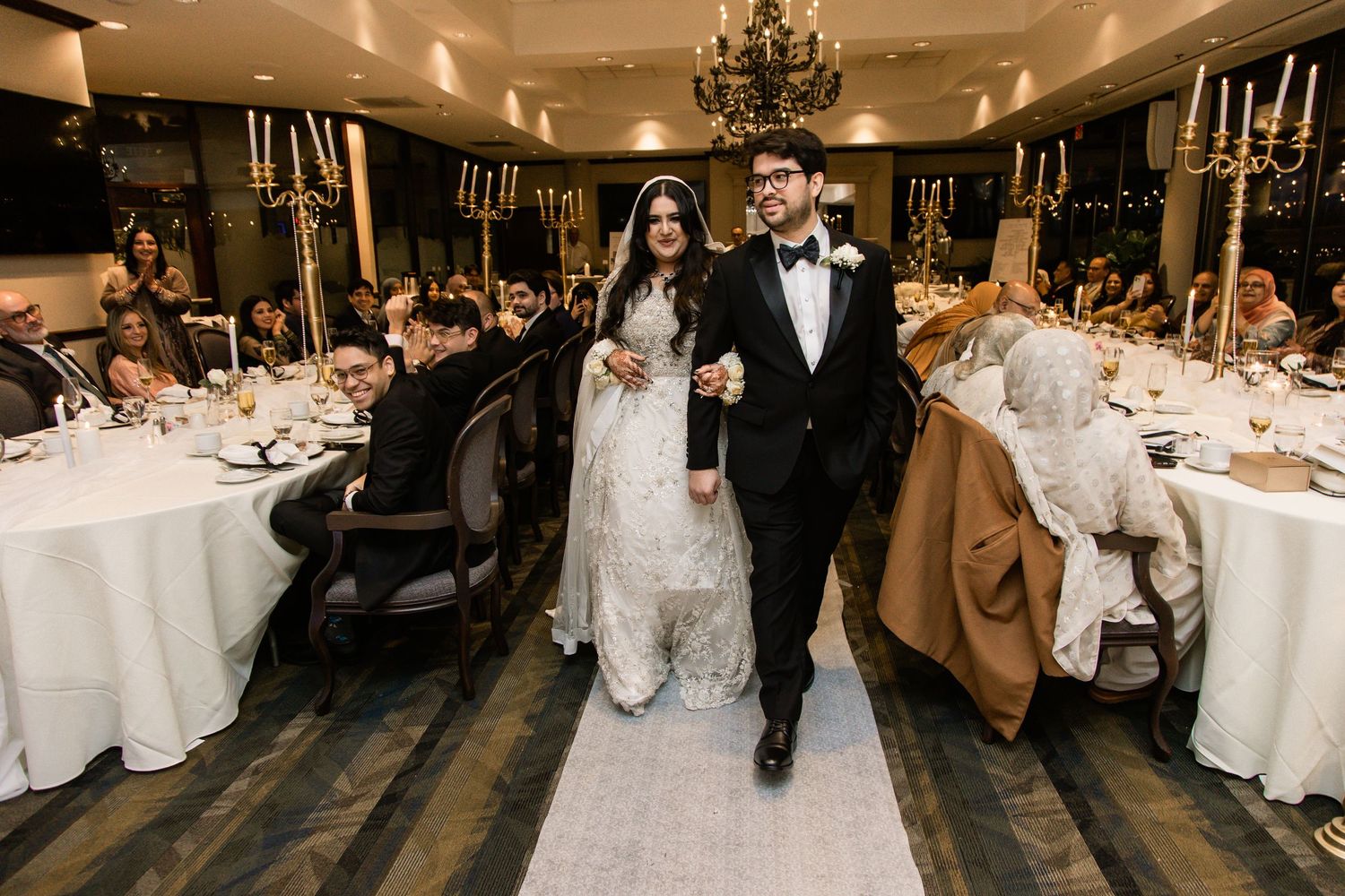 Bride and groom walking through banquet hall at wedding reception