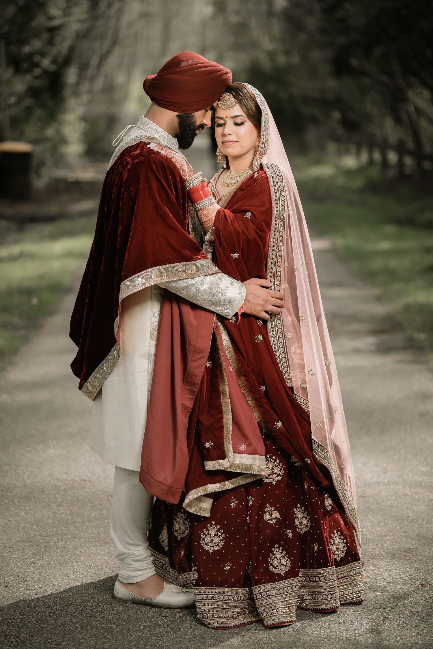 Sikh bride in red and gold bridal outfit with veil, outdoor portrait