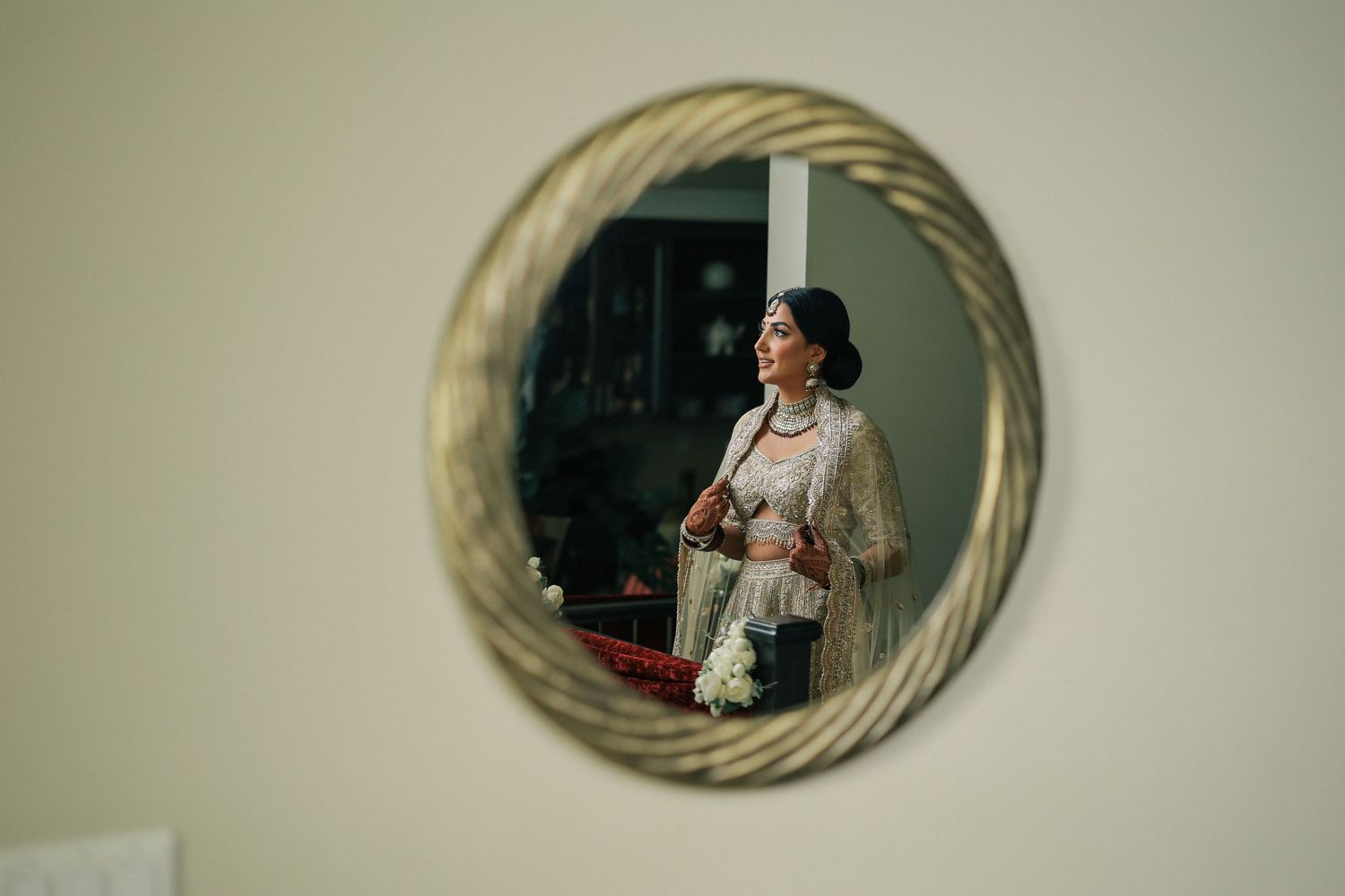 Bride reflected in round mirror during wedding morning preparations