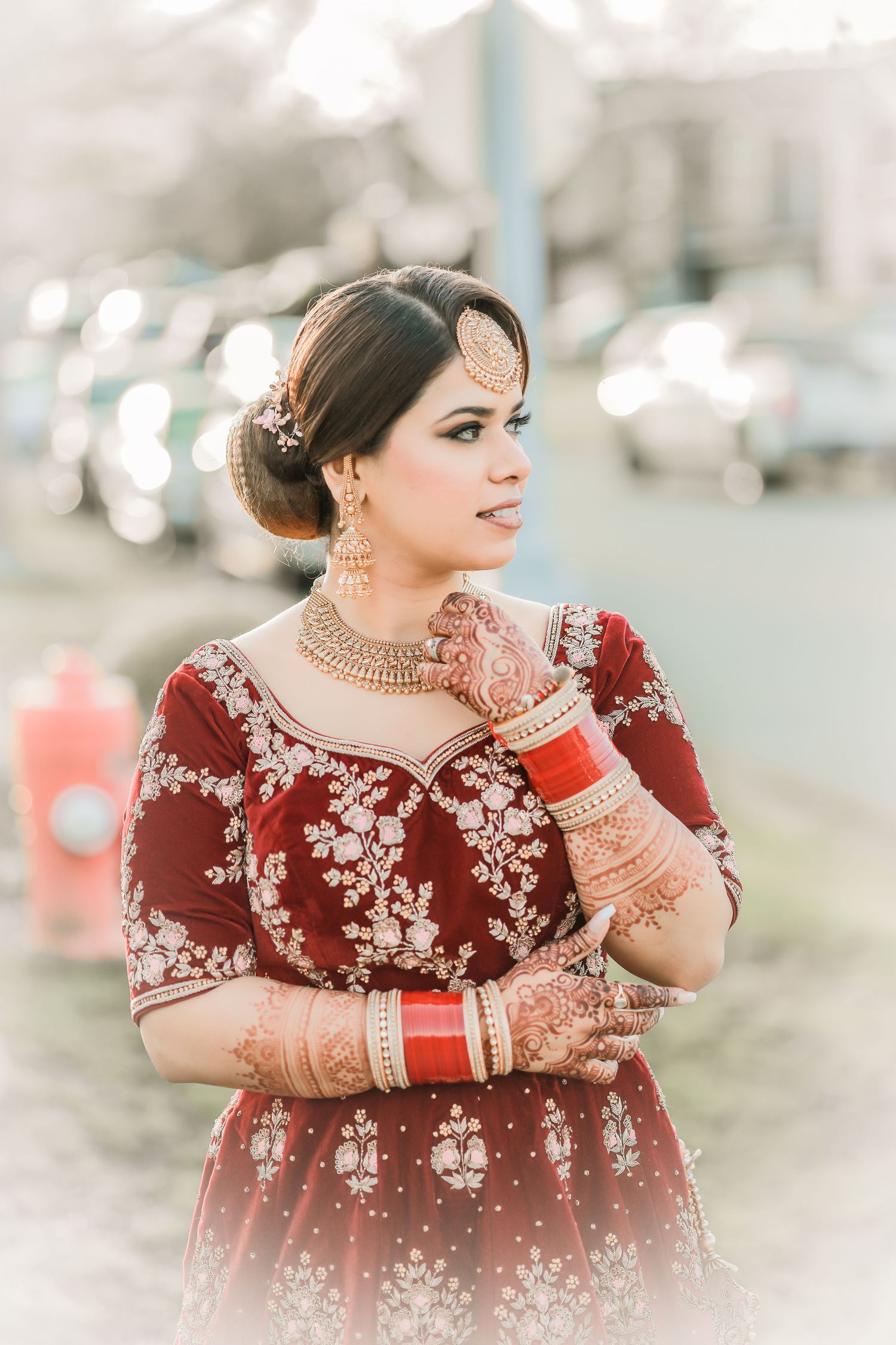 Bride in maroon and gold wedding lehenga, outdoor portrait