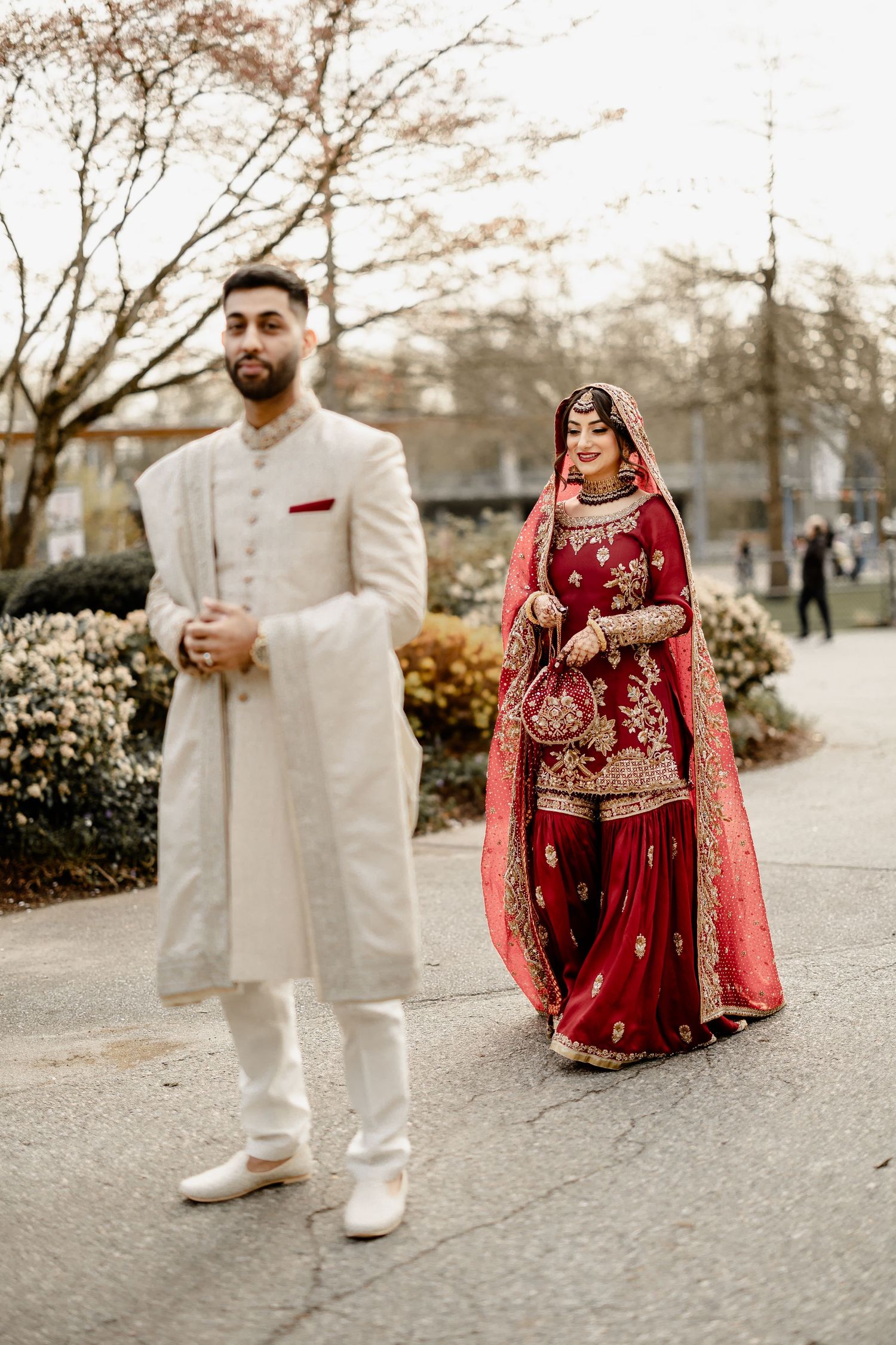 Groom in white kurta and bride in red bridal lehenga, South Asian wedding