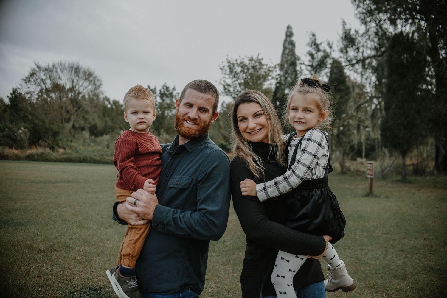 Family portrait session in a casual outdoor setting with natural greenery.