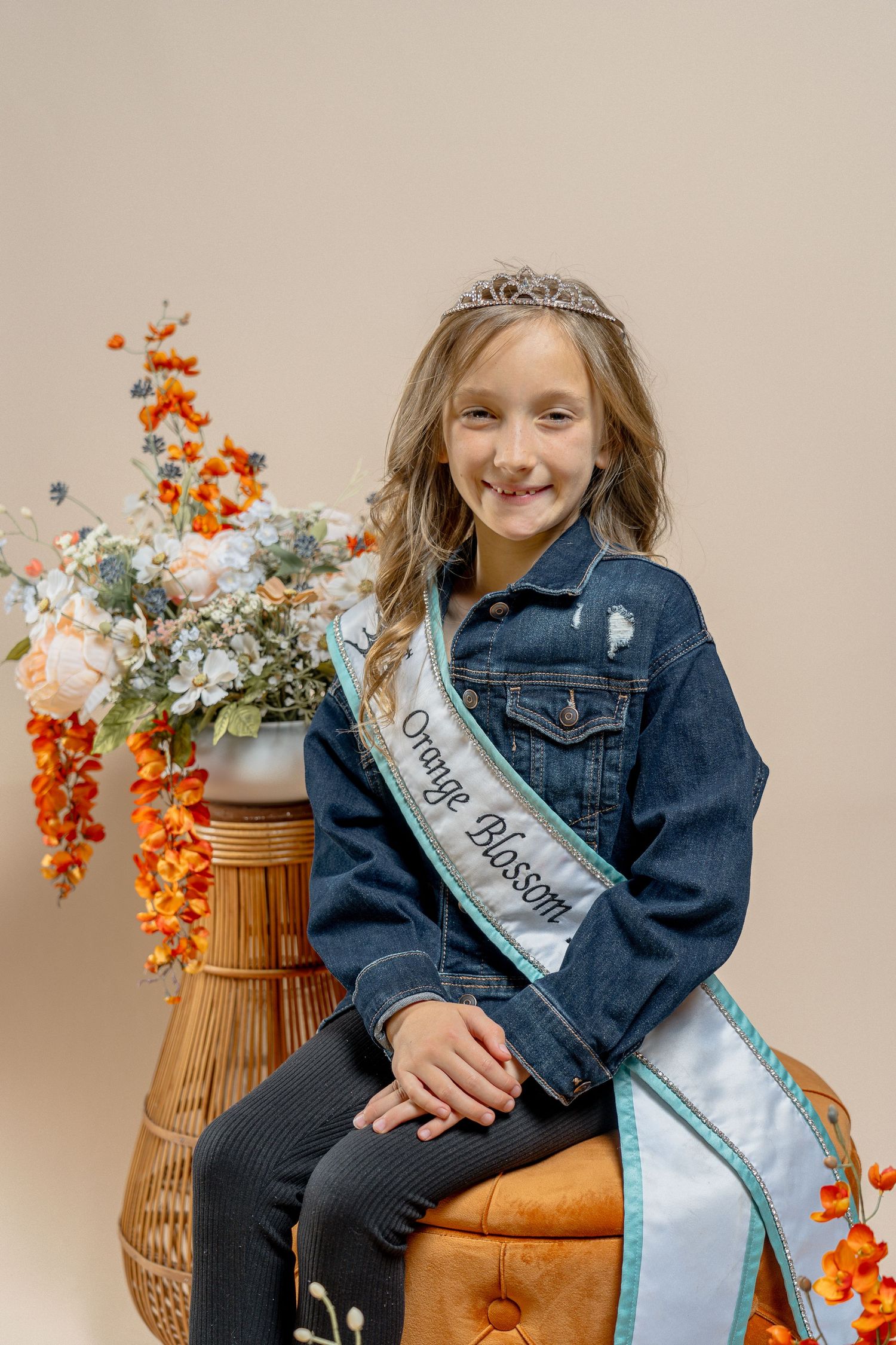 Pageant photoshoot with autumn flowers and wicker chair decorations.