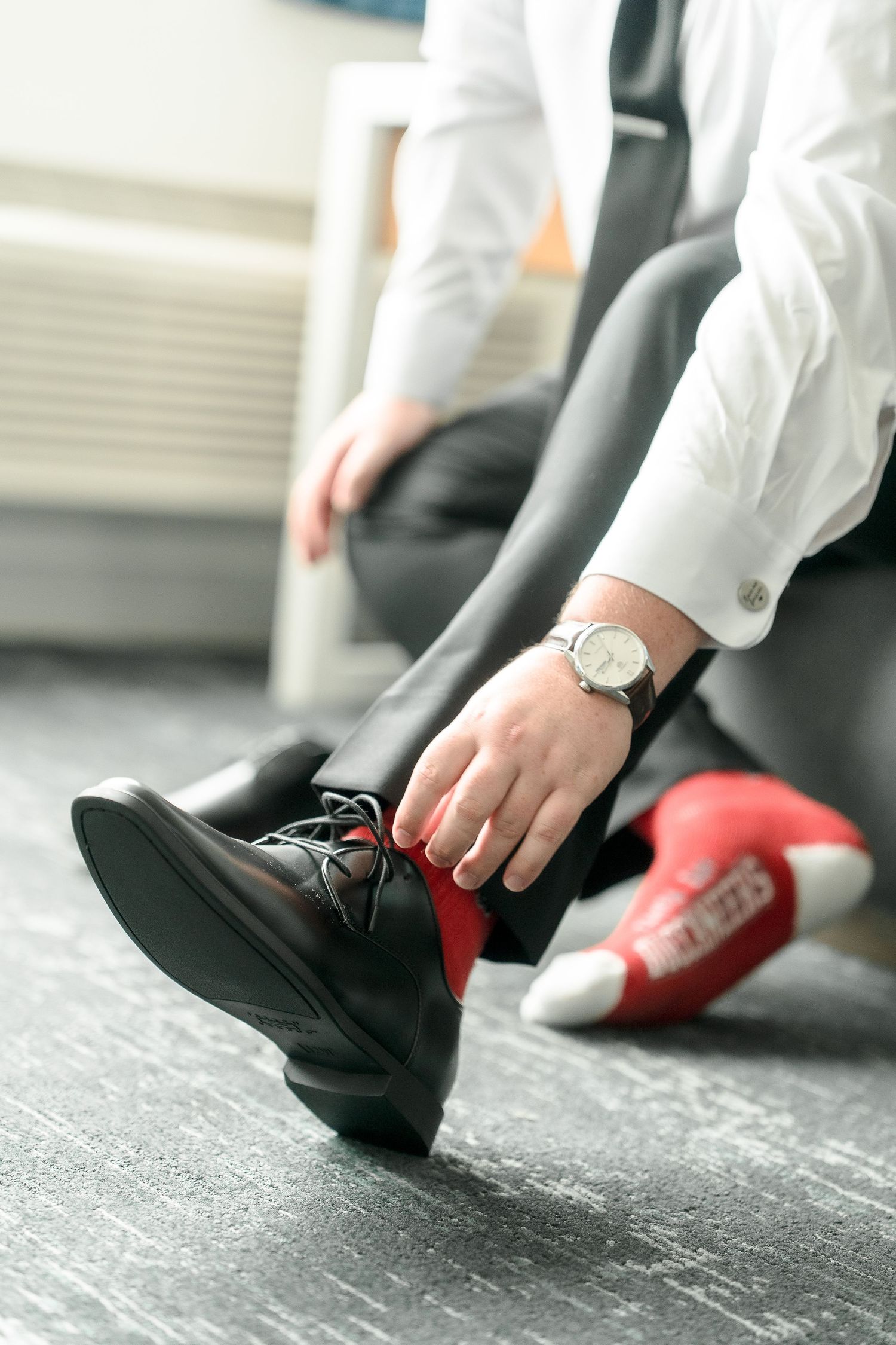 Close-up of feet putting on formal black and red dress shoes.