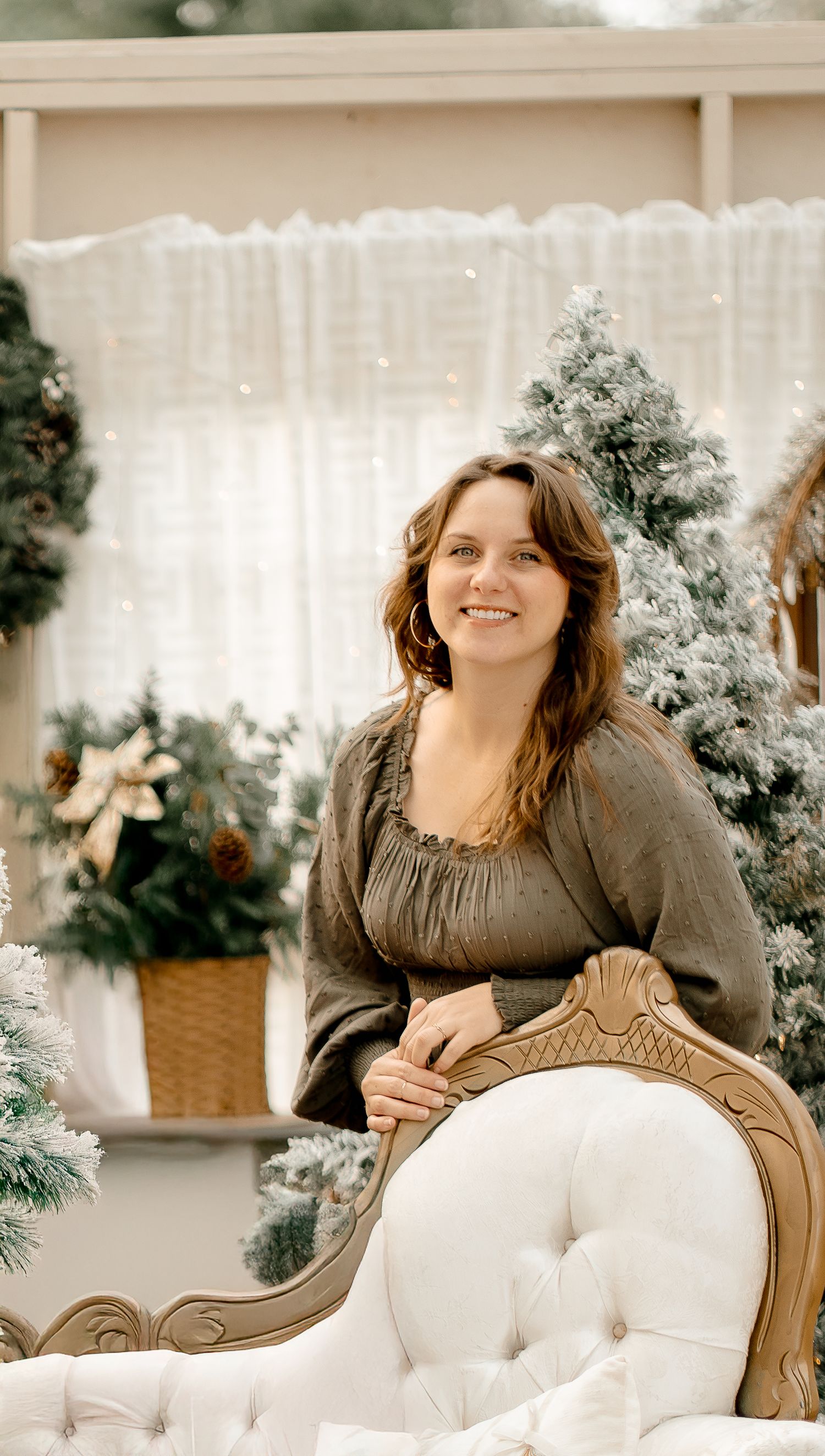 Portrait session on white tufted furniture with winter greenery and soft lighting.