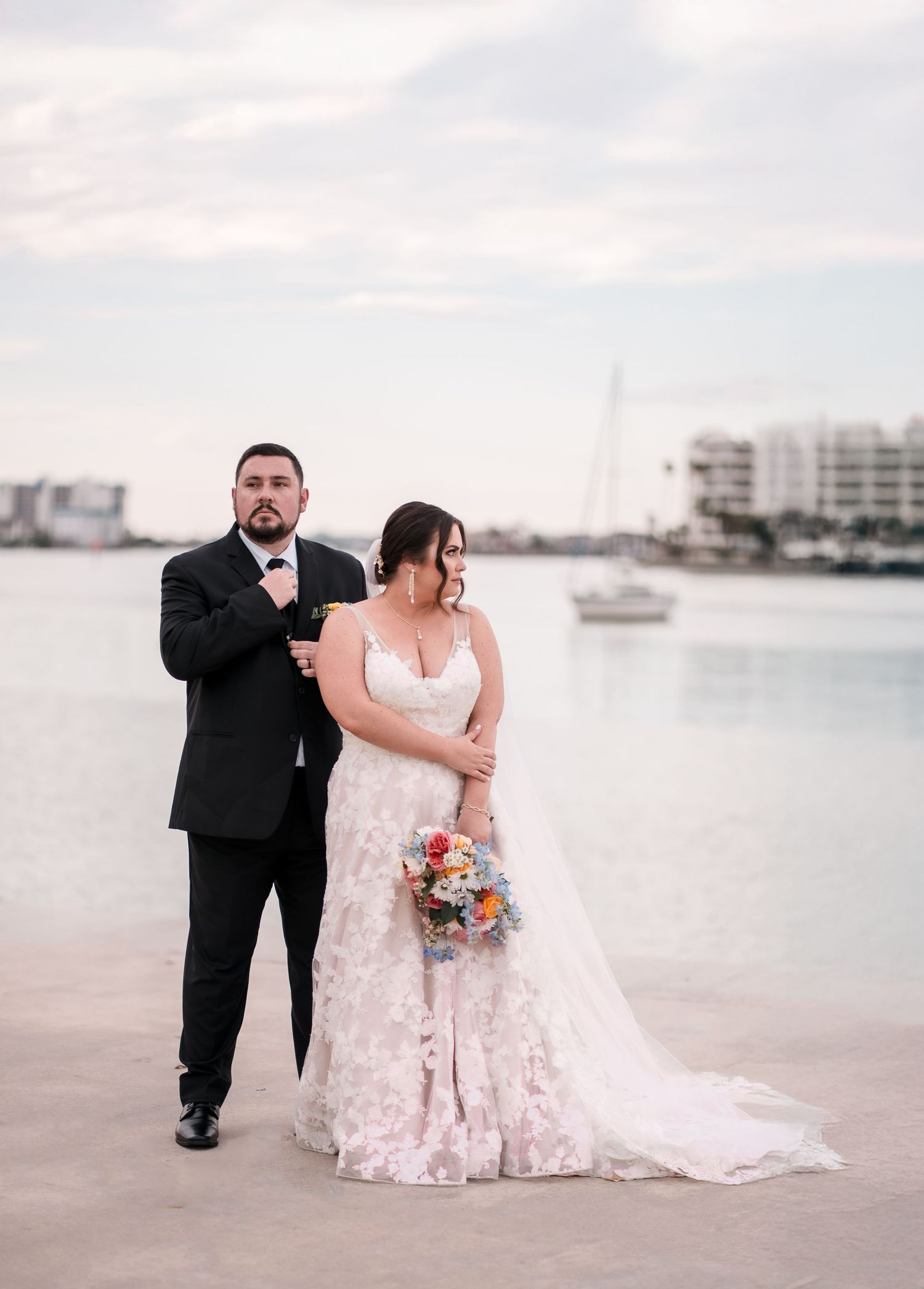 A waterfront wedding portrait with marina and sailboats in the background.