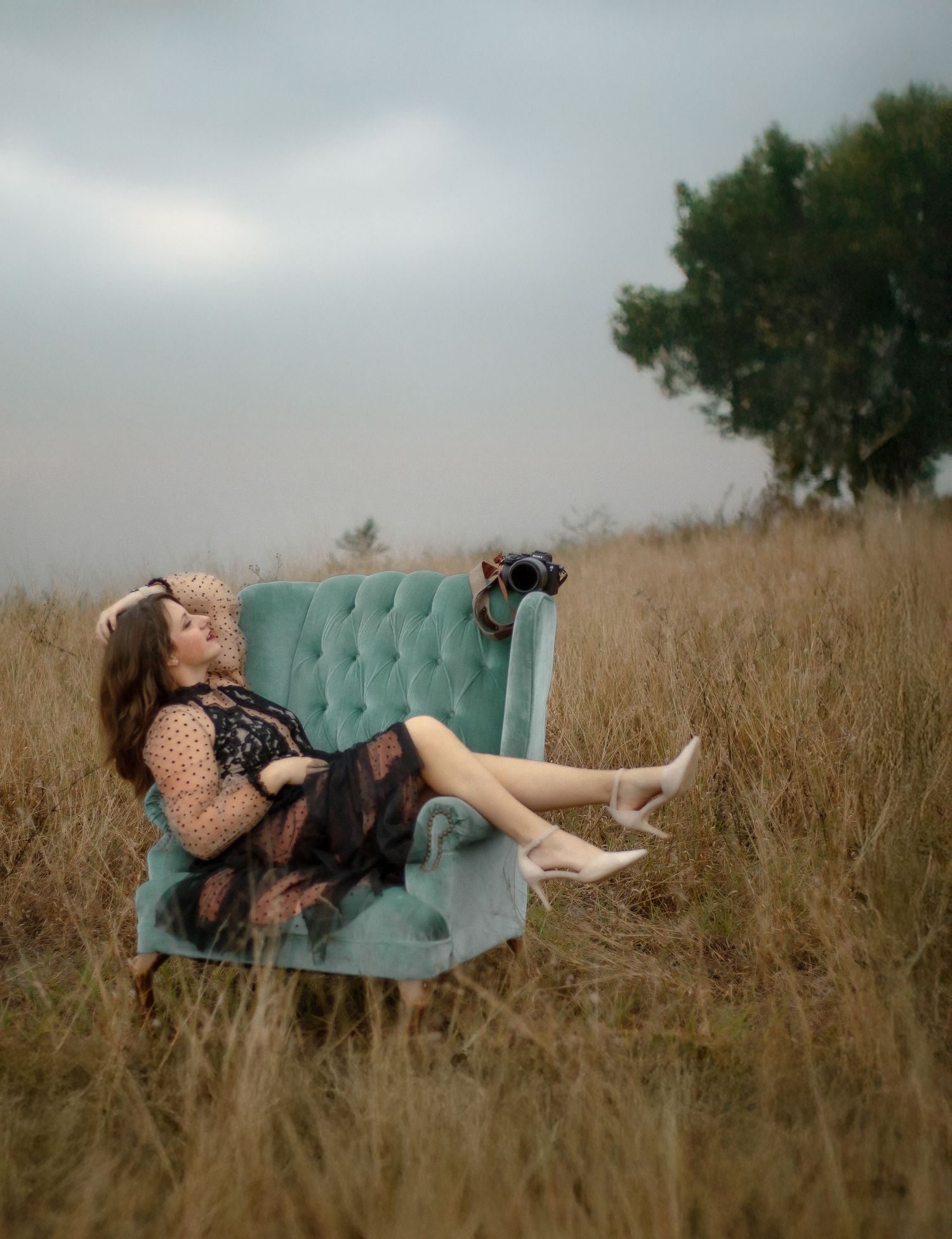 A dreamy photo shoot scene with a teal couch placed in tall grass during golden hour.
