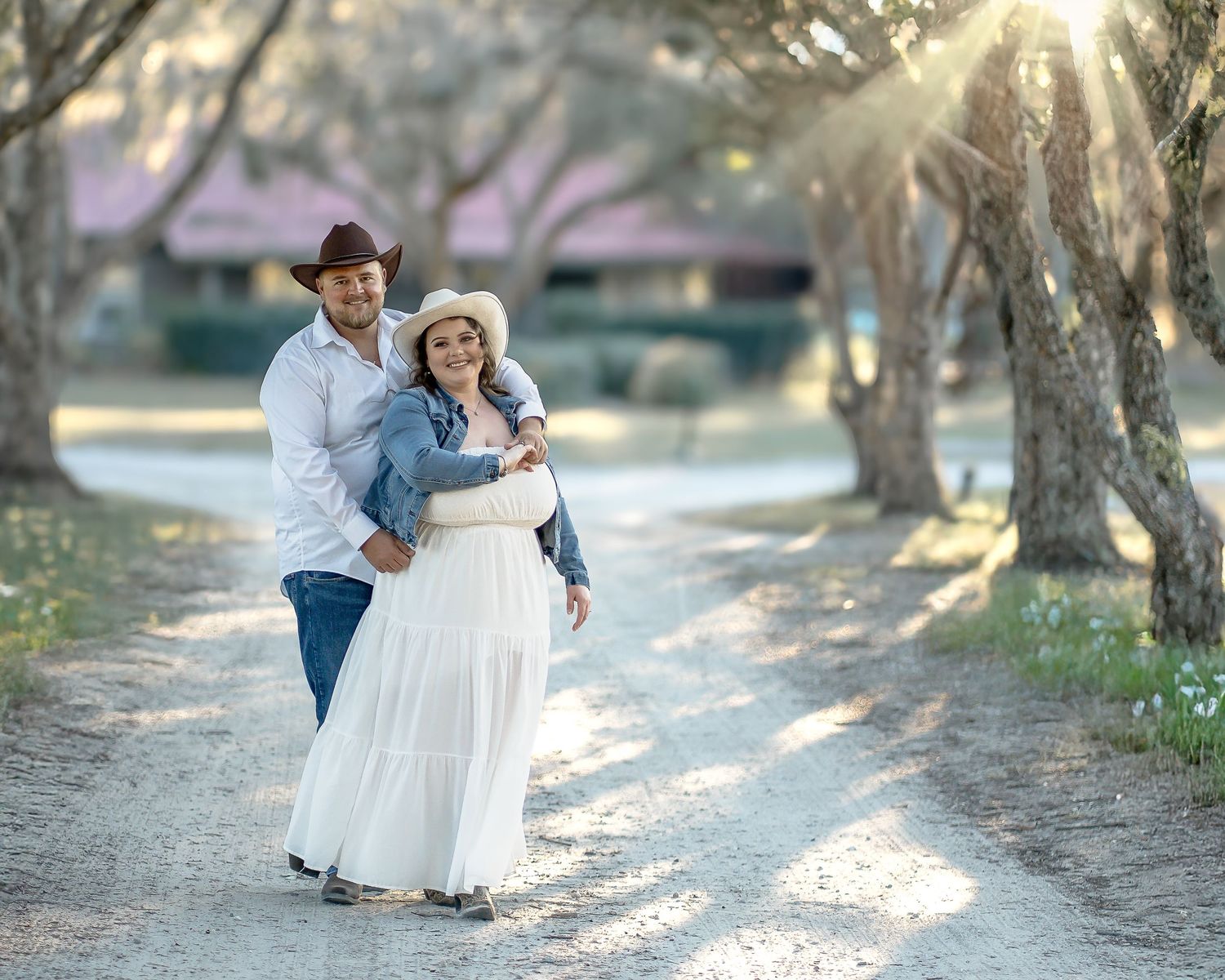 A romantic couple photoshoot in a sunlit path with trees.