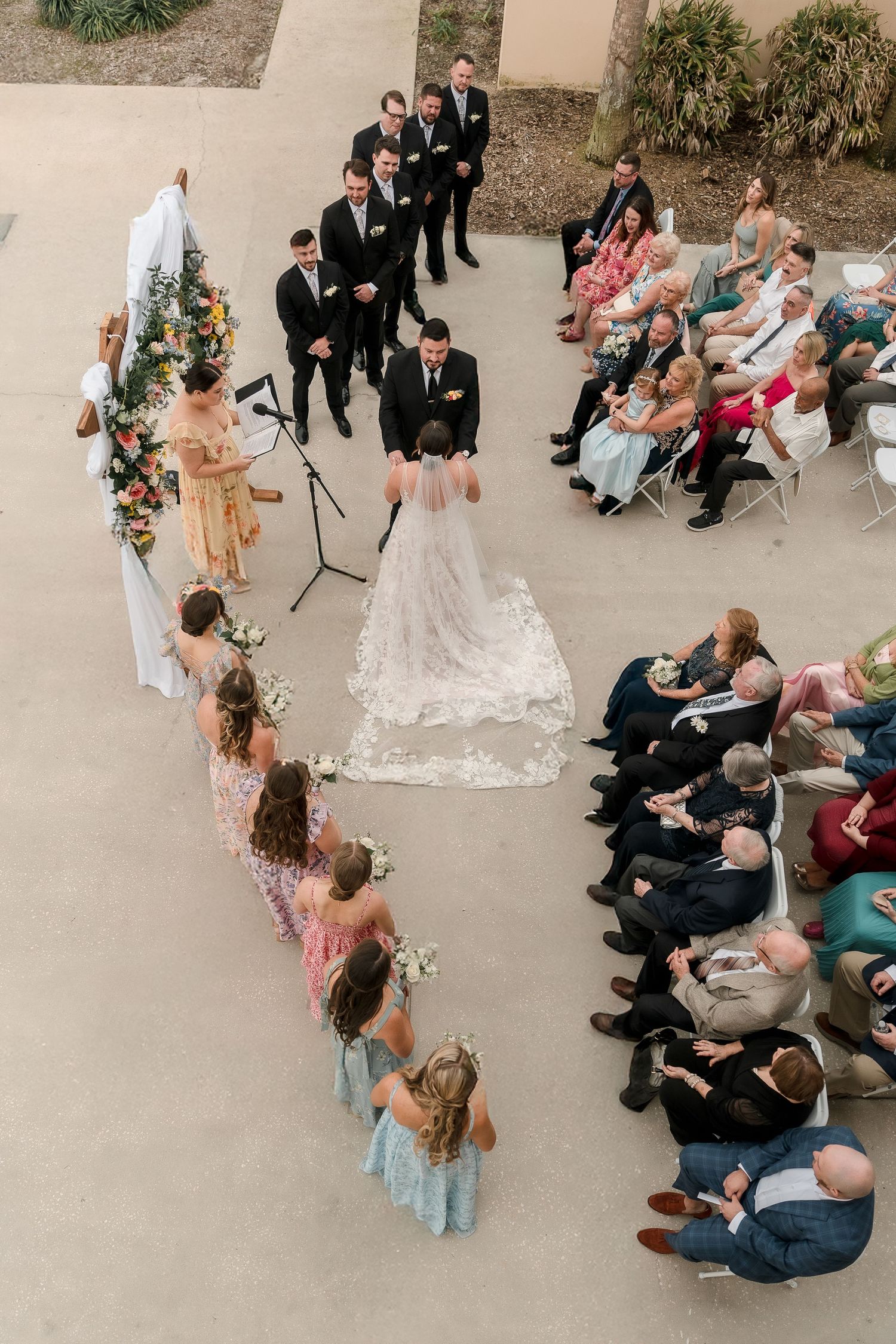 Aerial view of an outdoor wedding ceremony with guests seated in rows.