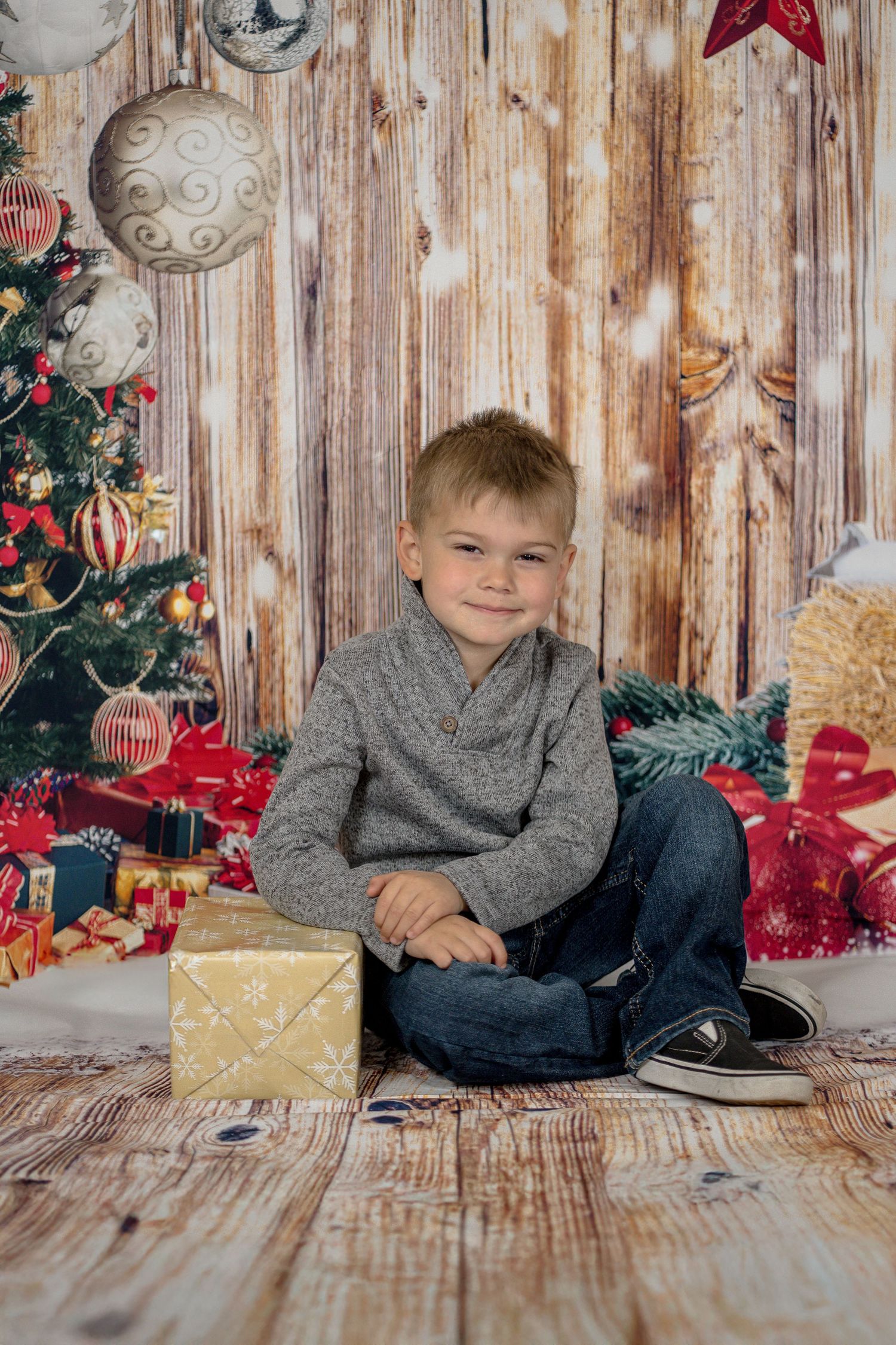 Holiday themed photo shoot with rustic wooden backdrop, ornaments, and festive decorations.