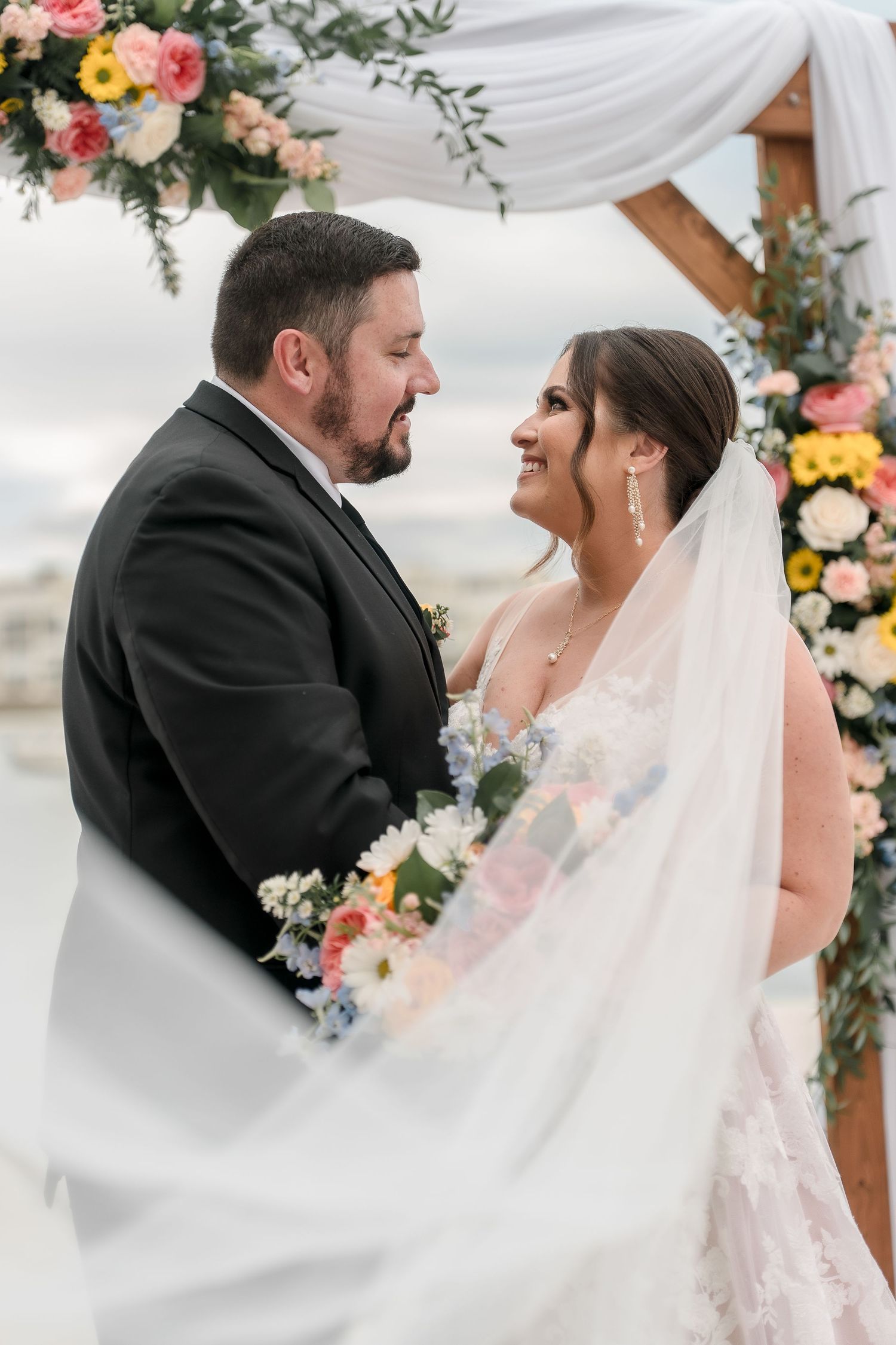 Romantic moment between newlyweds under a floral wedding arch.