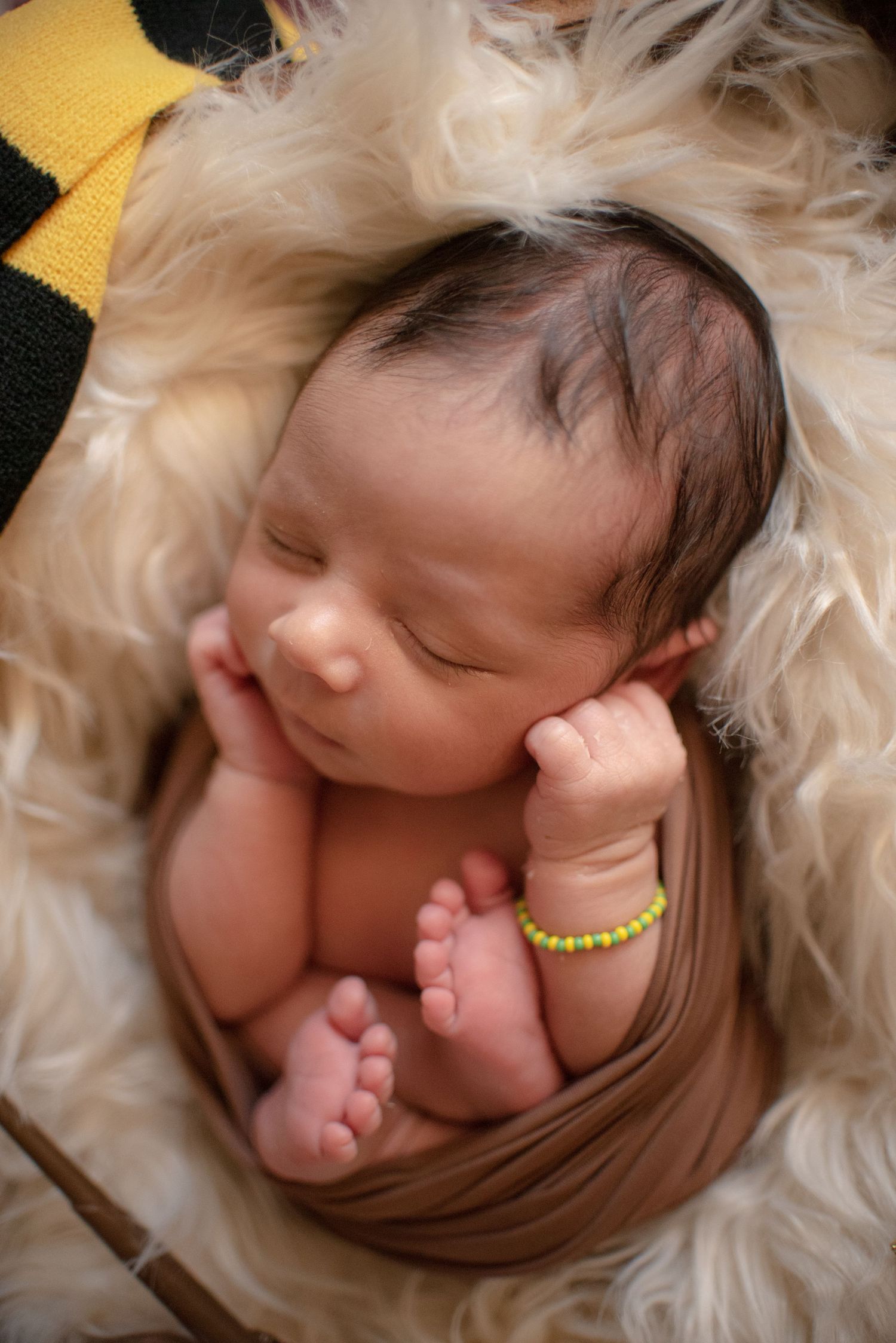 Close-up portrait of a sleeping newborn baby wrapped in soft white fur.