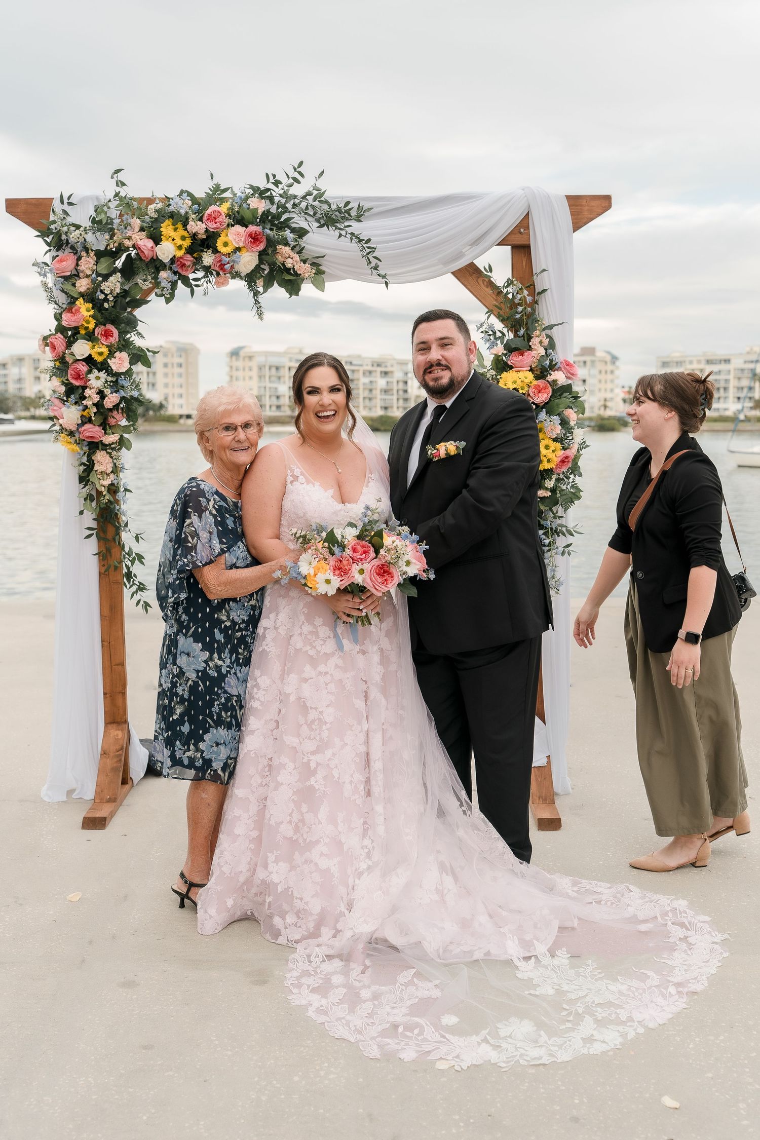 Beach wedding ceremony setup with floral arch and pink dress details.