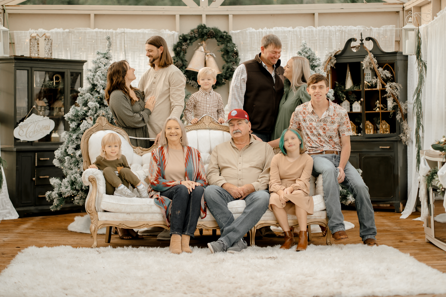A group of people sitting on a white carpet in a cozy living room during a casual gathering.