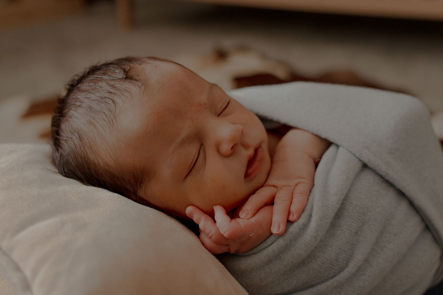 Close-up shots of a sleeping newborn baby wrapped in soft gray blankets.