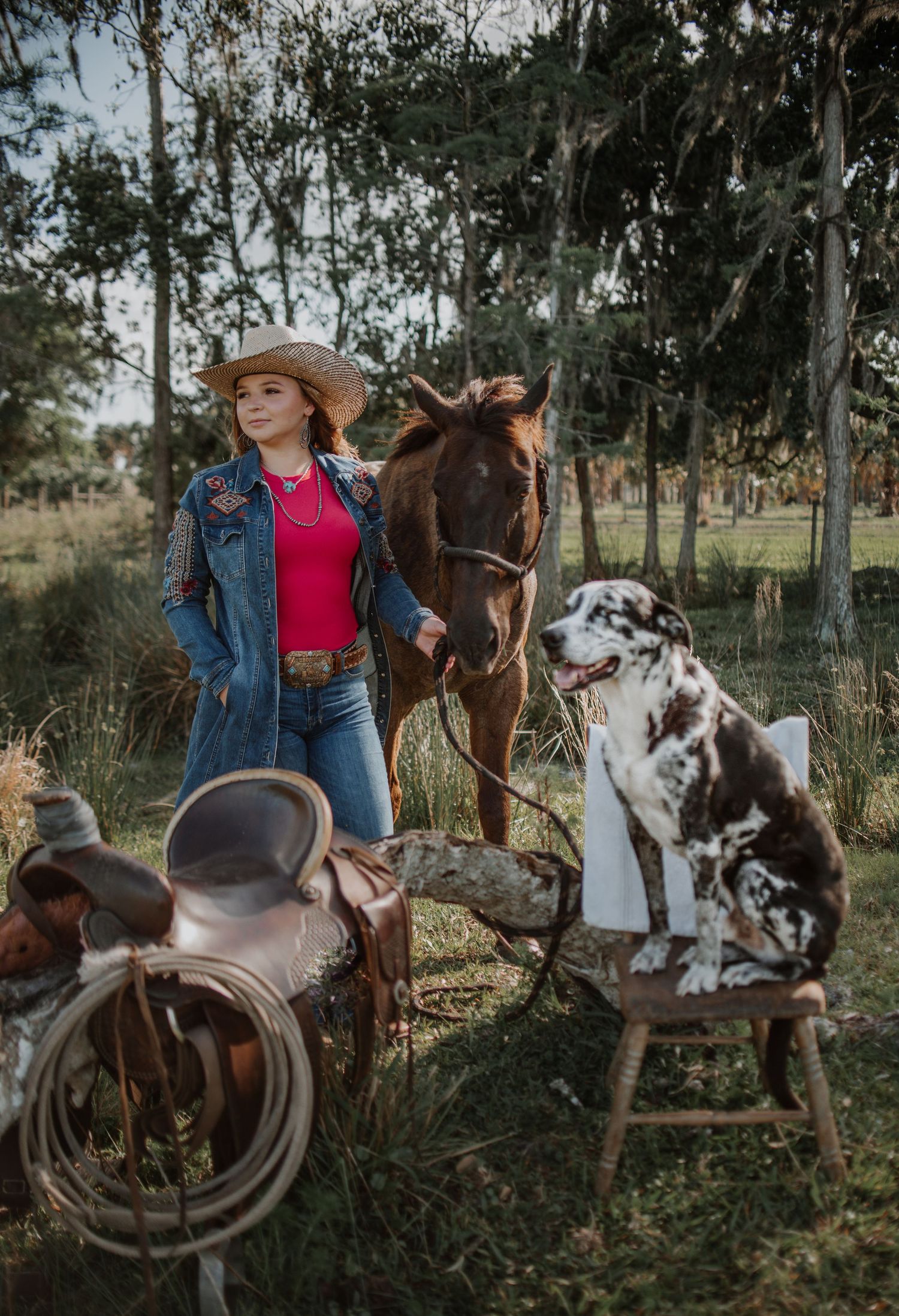 Casual photoshoot with horses and western-style props in a wooded setting.