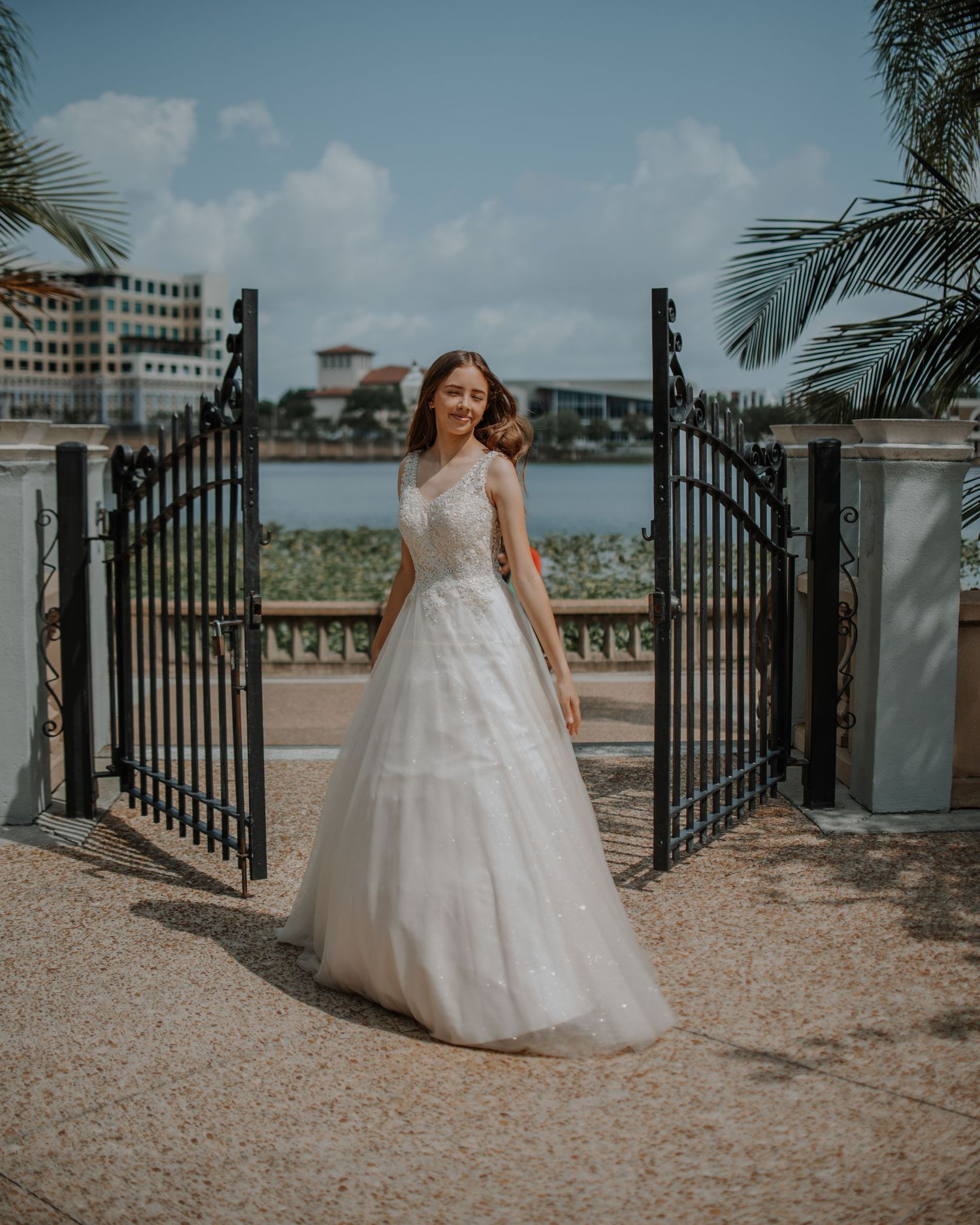 Bridal portrait at beachfront gate entrance with white ballgown and ocean view.