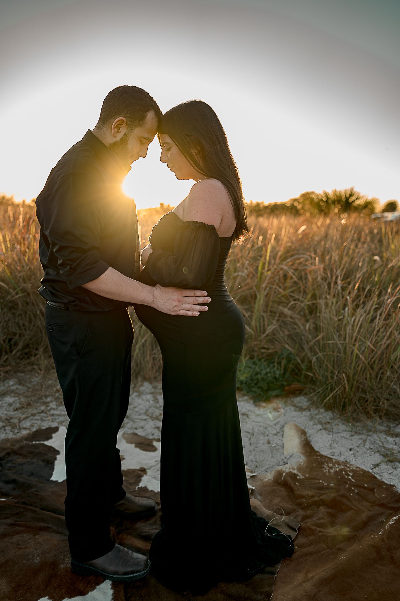 Silhouetted couple shares intimate moments on a beach at sunset.