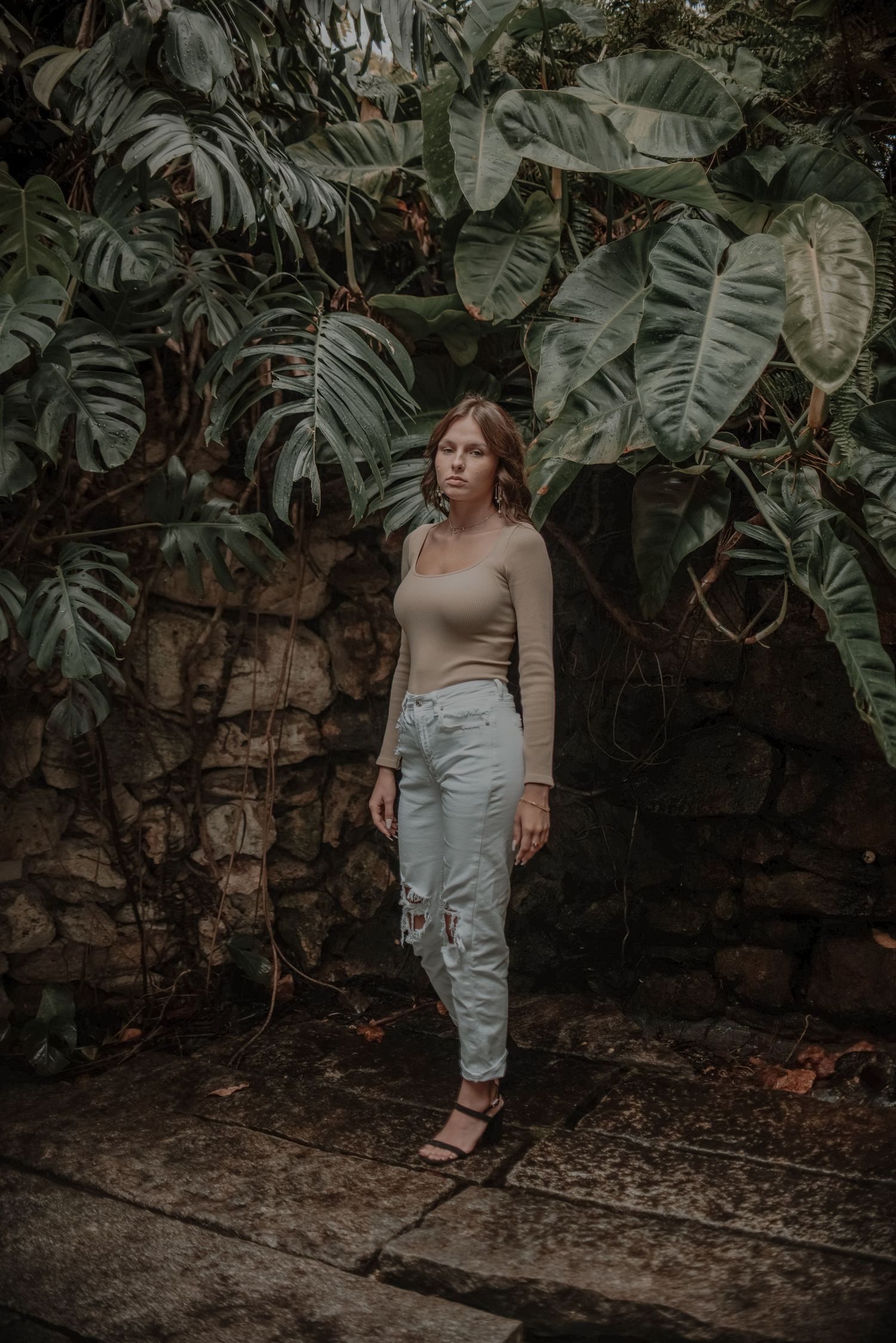 Elegant portrait in a garden setting with large tropical monstera leaves.