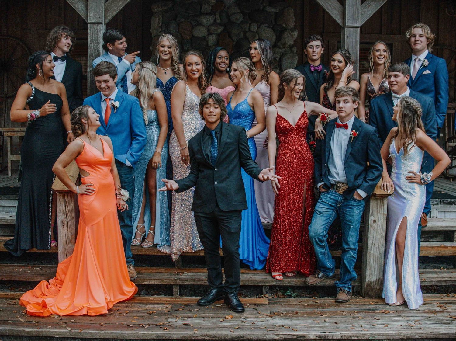 Panoramic view of formal event attendees gathered outside in elegant dresses and suits.