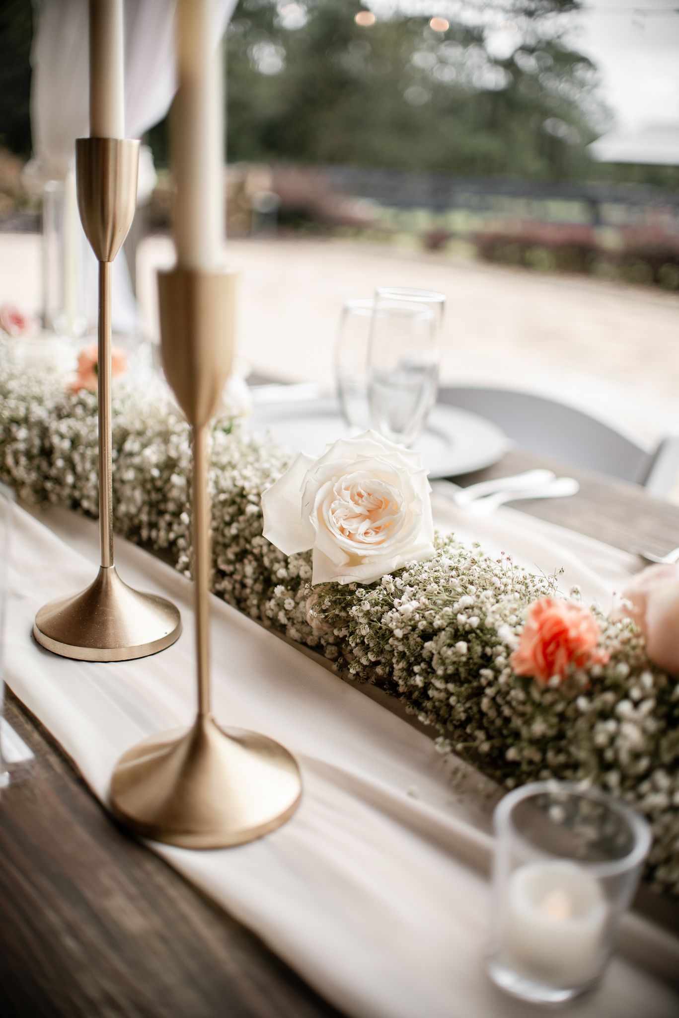 Elegant wedding table decor features gold candlesticks and delicate baby's breath floral arrangements.