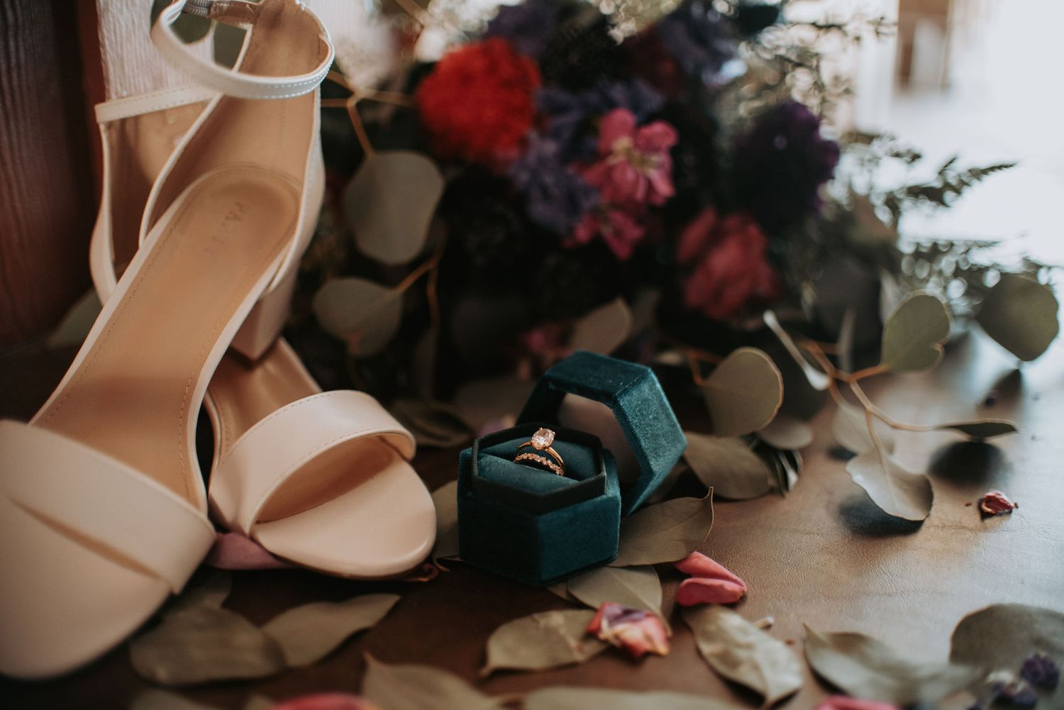 Wedding shoes and floral arrangements artistically arranged on a textured surface.