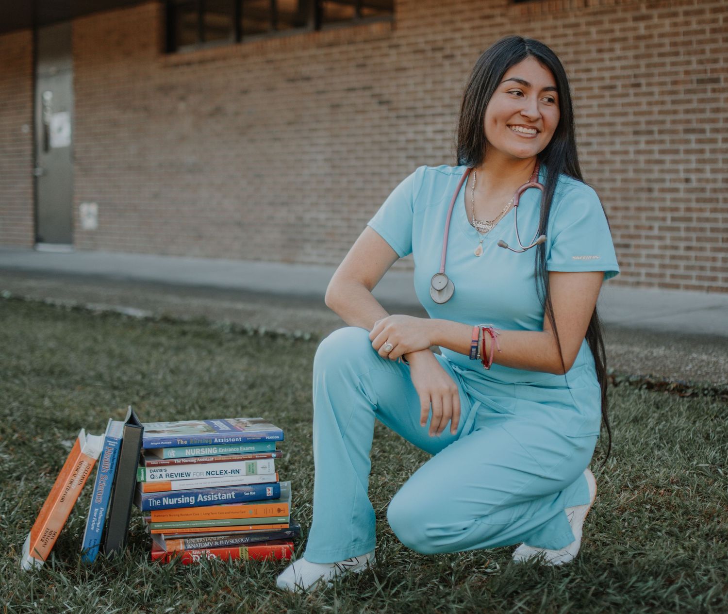A collection of five photos showing someone in a blue dress sitting on grass with stacks of books beside them.
