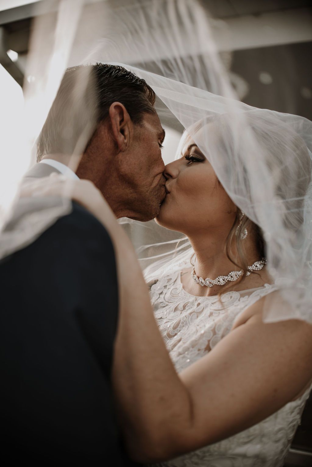Intimate wedding portrait capturing a romantic moment under a flowing veil.