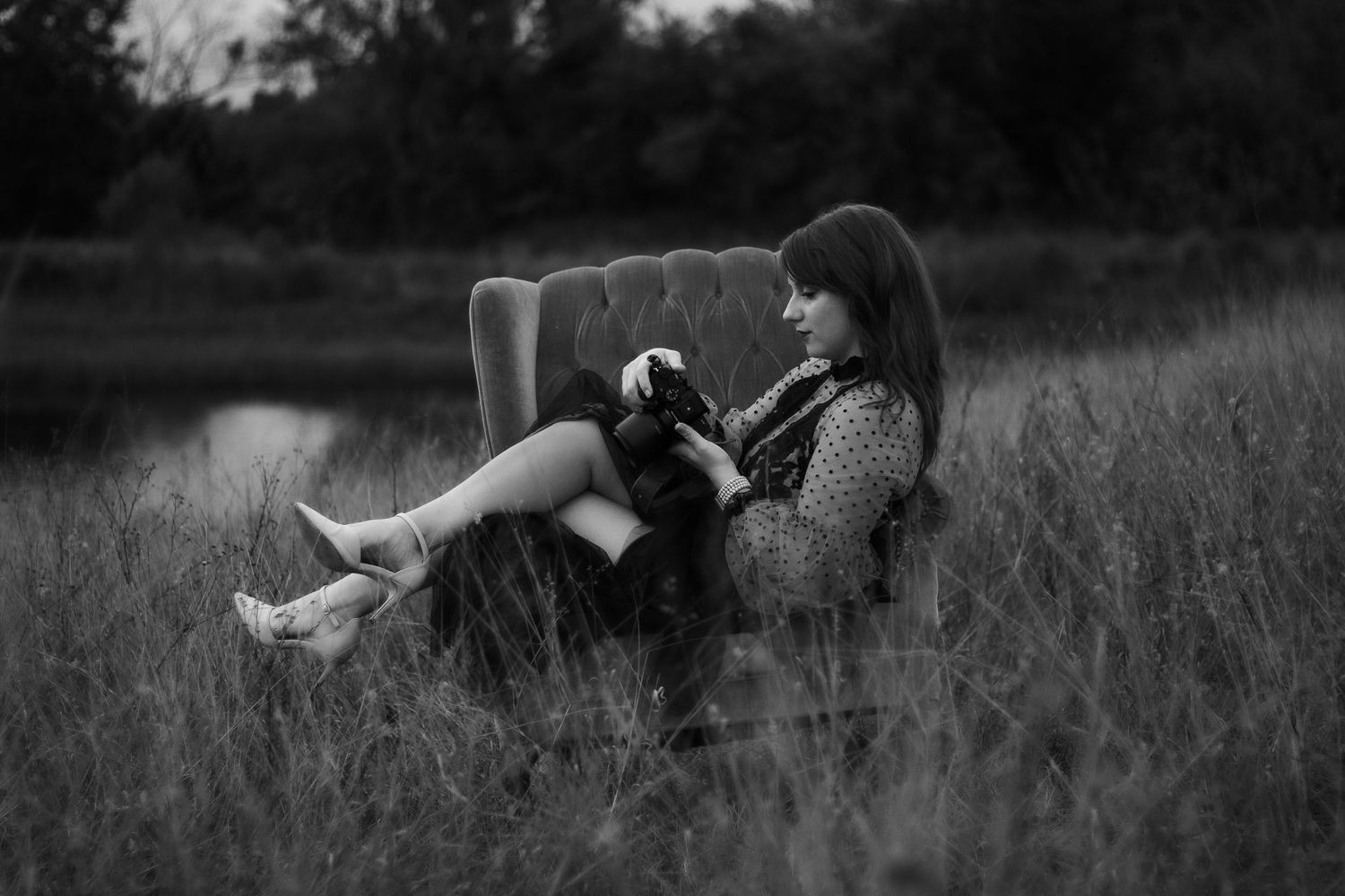 Black and white artistic photo of a vintage teal sofa in a field.