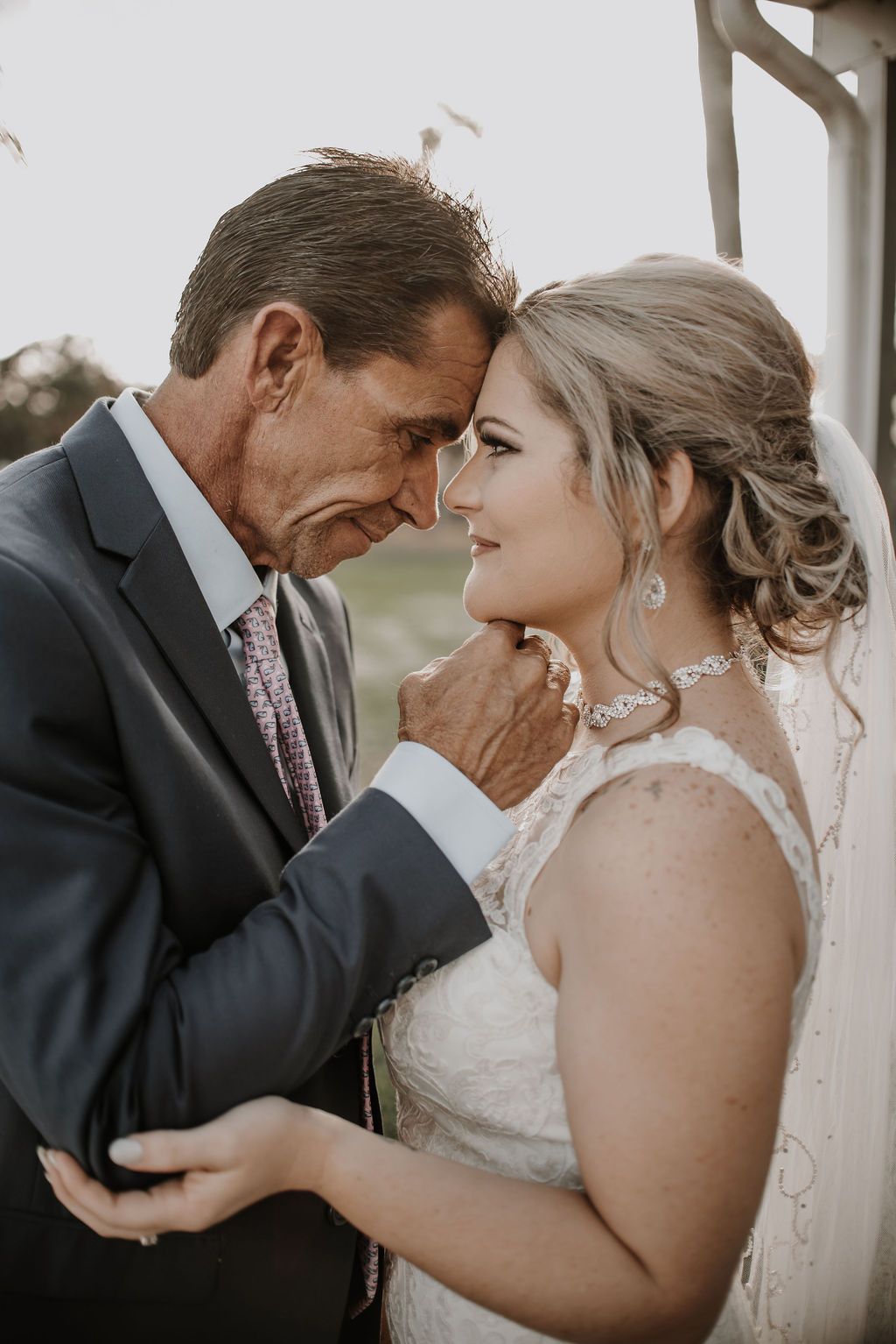 Emotional wedding day moment between a couple sharing tender glances during their outdoor ceremony.