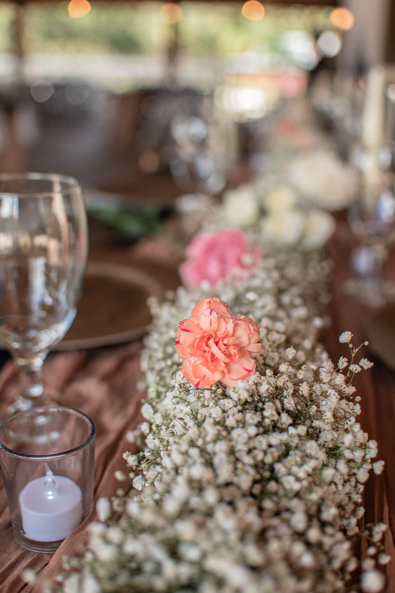 Wedding reception table with delicate pink carnations and baby's breath centerpiece.