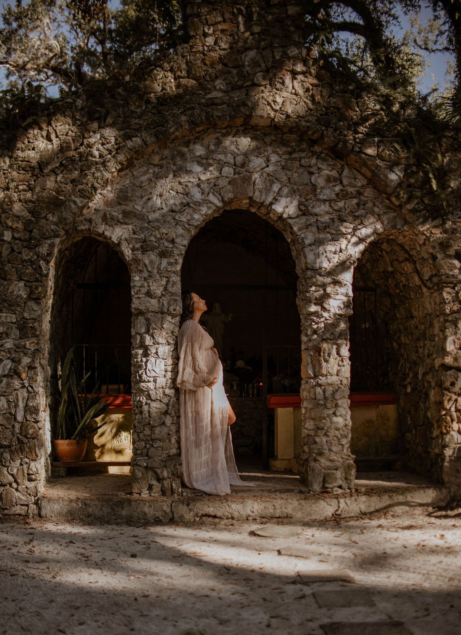 Ethereal bridal portrait in stone archway with dramatic lighting.