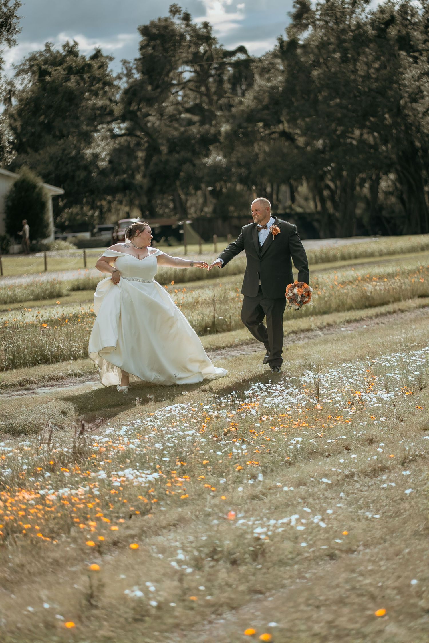 Couple runs joyfully through a field of wildflowers on their wedding day.