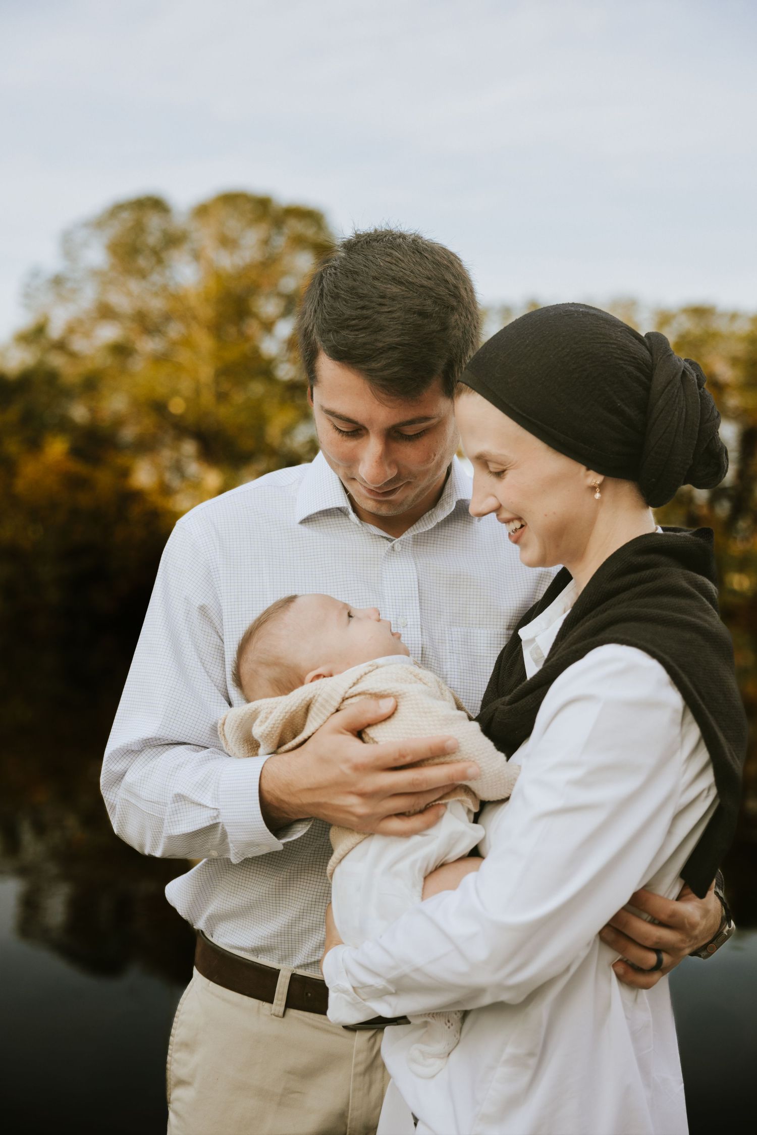 Father and Mother holding her newborn during an out-door newborn photography session in Augusta,