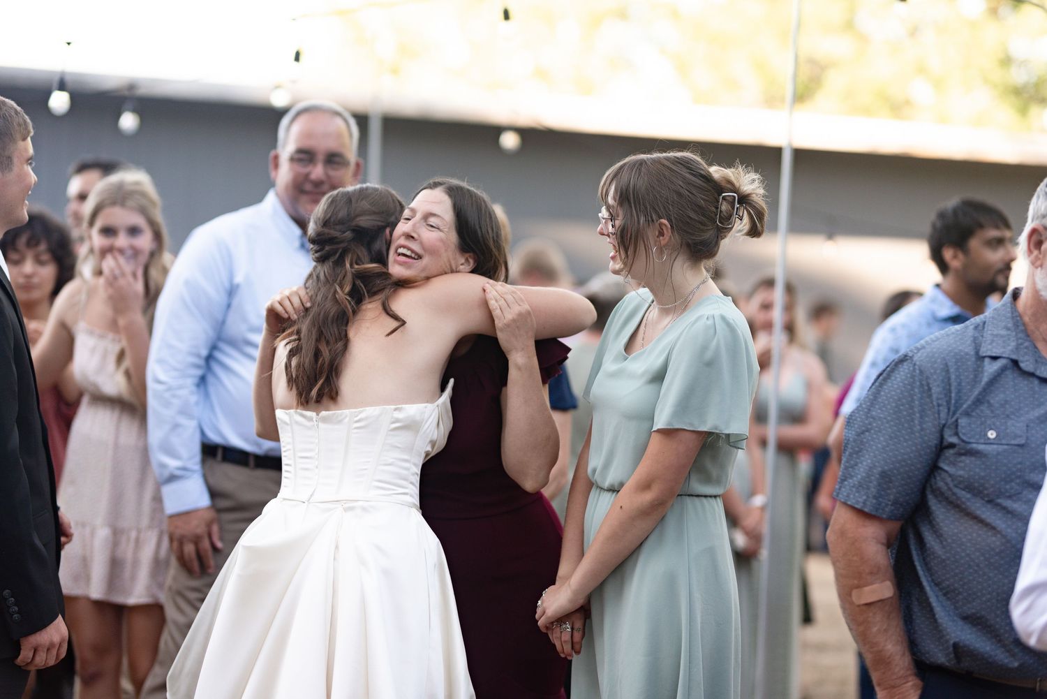 Bride sharing a joyful hug with a guest at an outdoor wedding celebration.