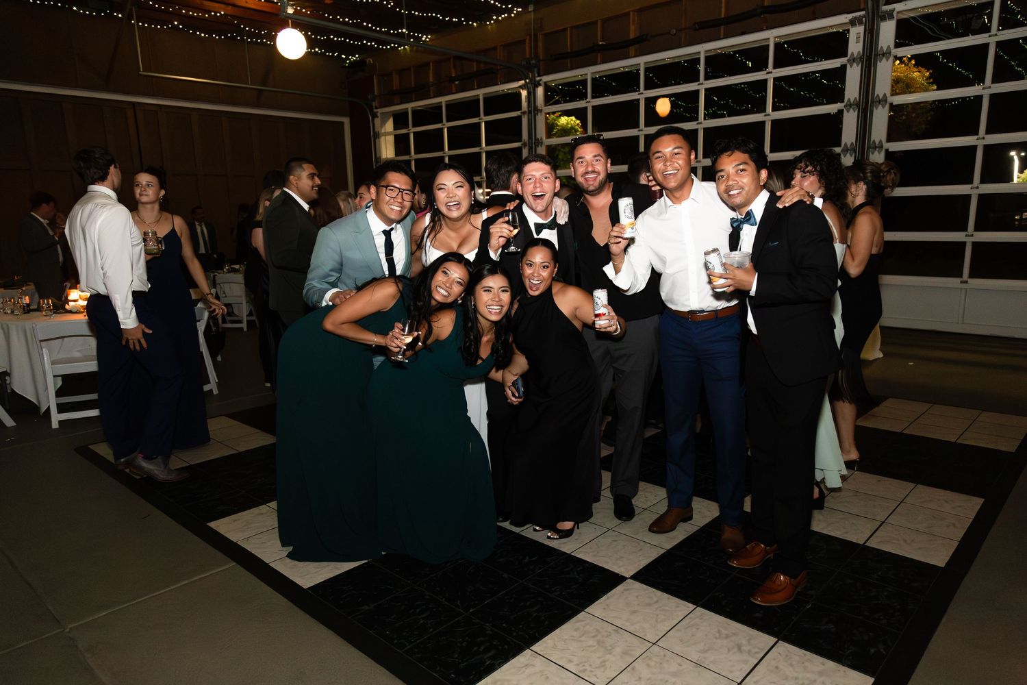 Group of wedding guests posing together on a black and white dance floor at reception.