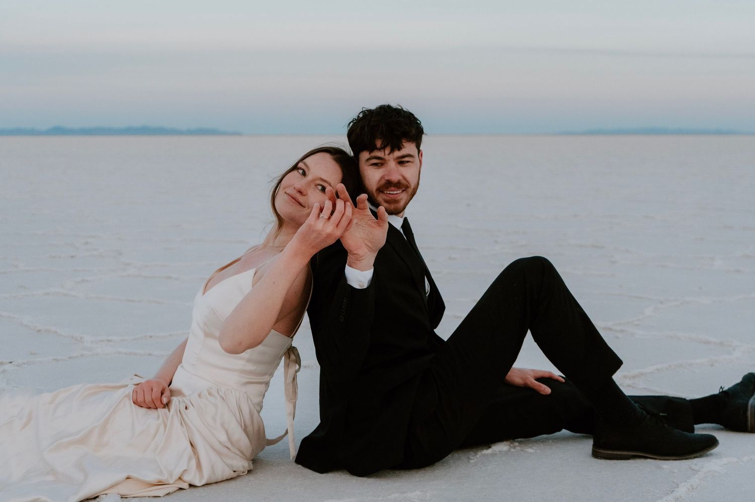 Bride and groom smiling while seated together at Bonneville Salt Flats bridal photos