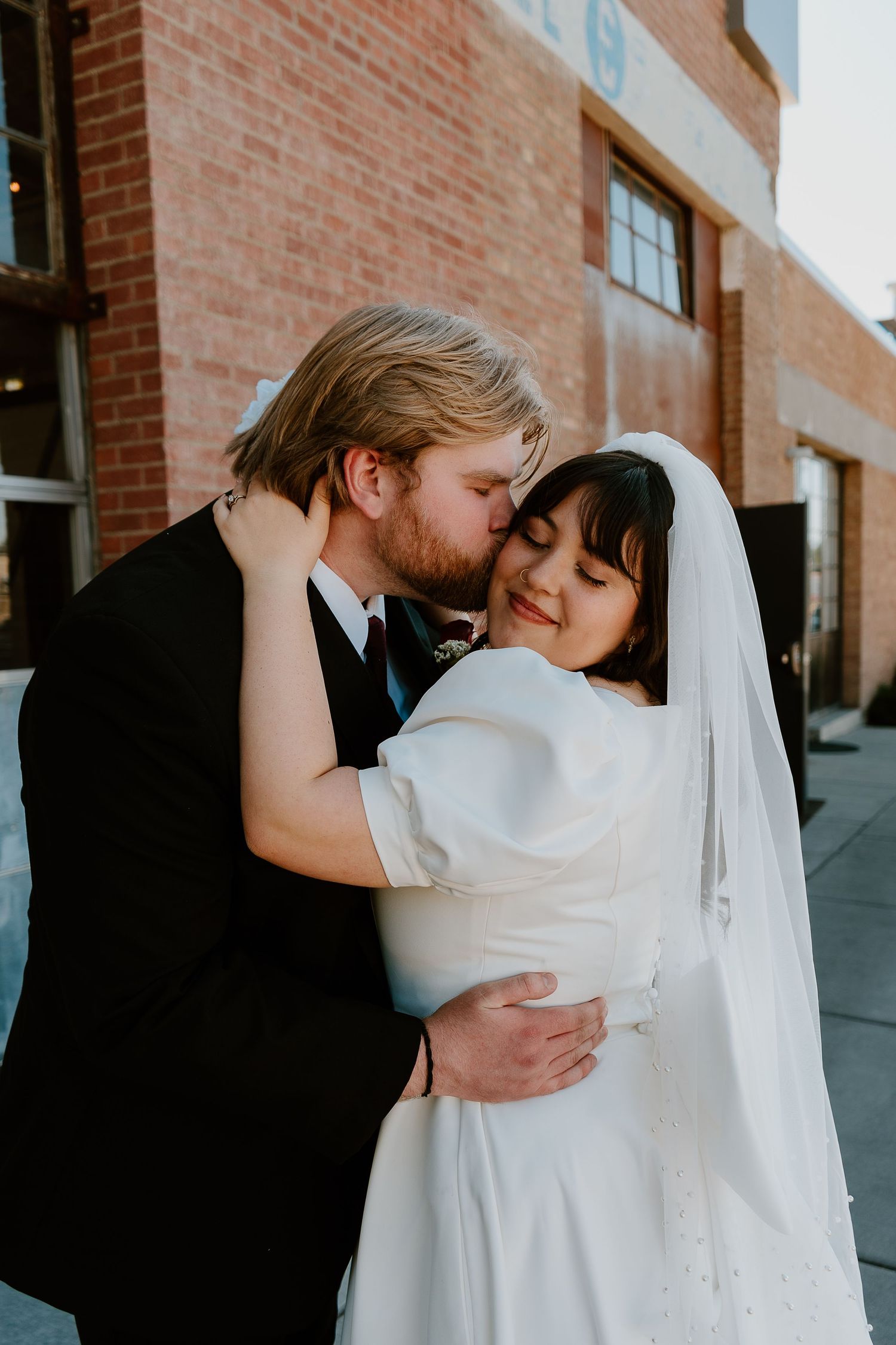 Bride and groom embracing during romantic downtown wedding portrait session