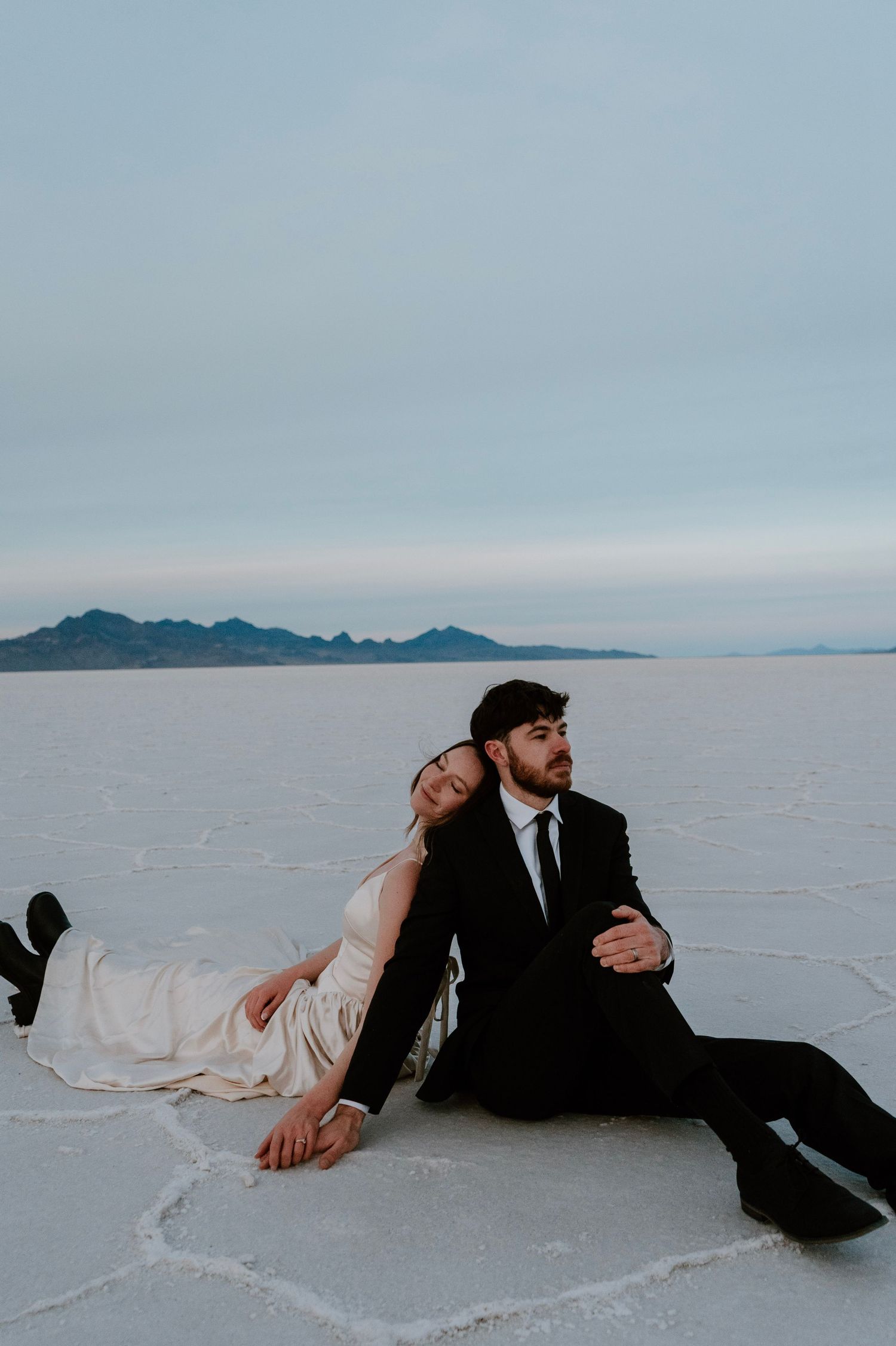 Bride and groom sitting together at Utah Salt Flats during romantic bridal session