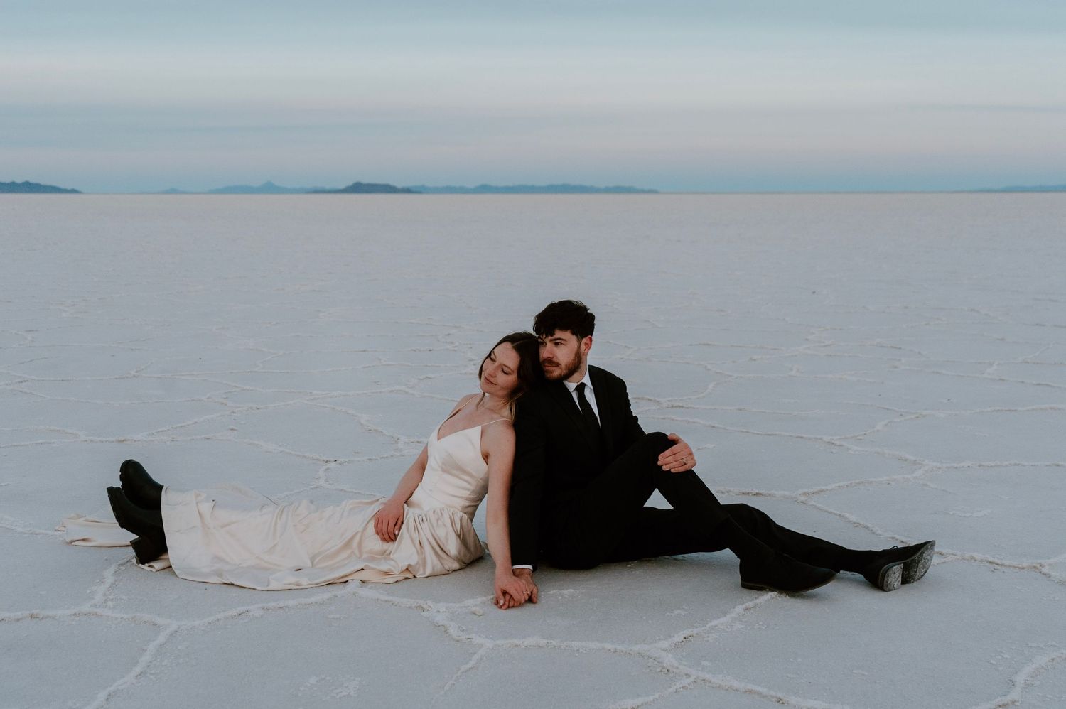 Romantic bride and groom lounging together during Utah Salt Flats bridal session