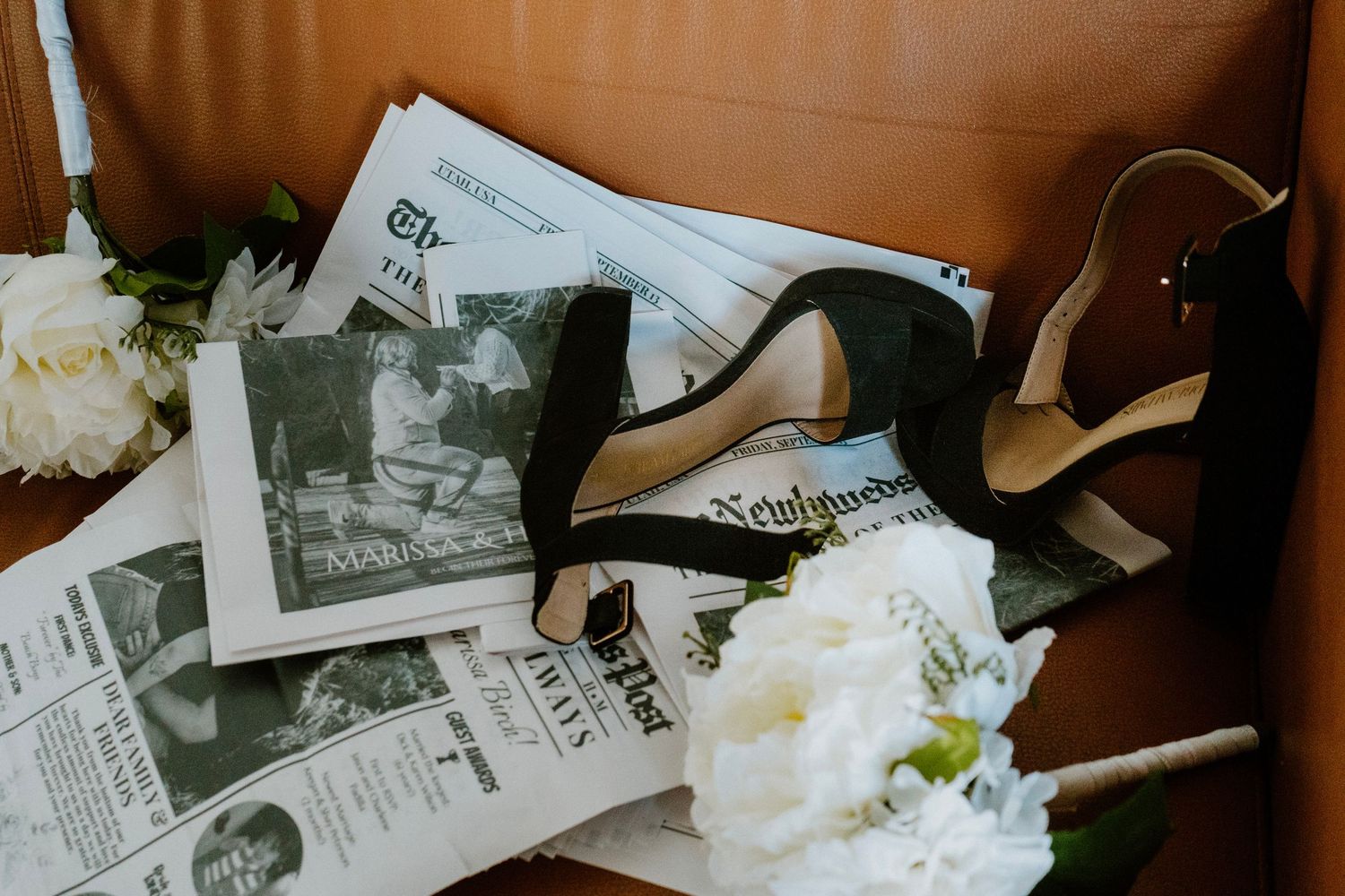 Wedding detail photo with bridal shoes, florals, and newspaper keepsakes